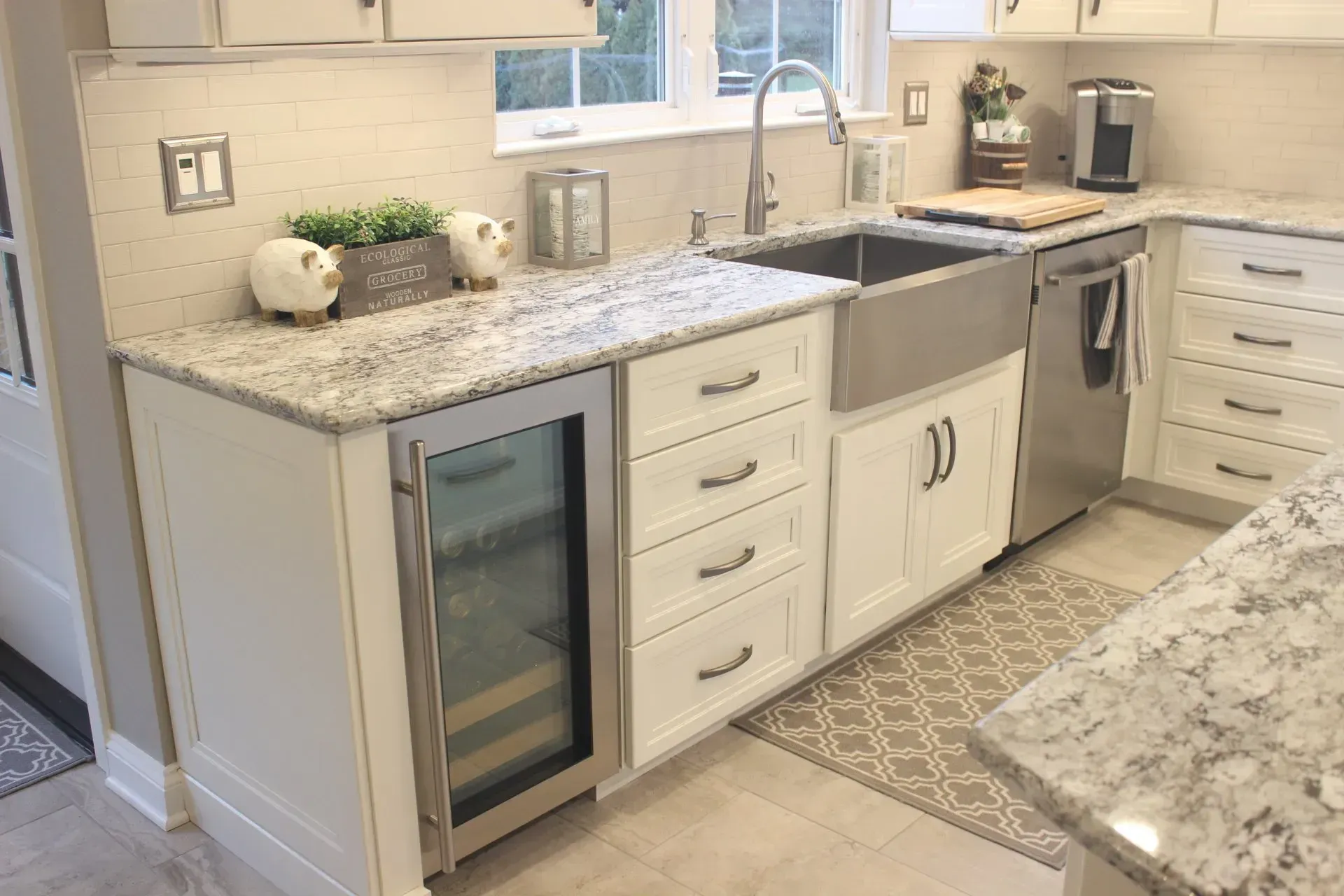 Modern kitchen with white cabinets, granite counters, stainless appliances, and a wine cooler under the counter In Bucks County PA
