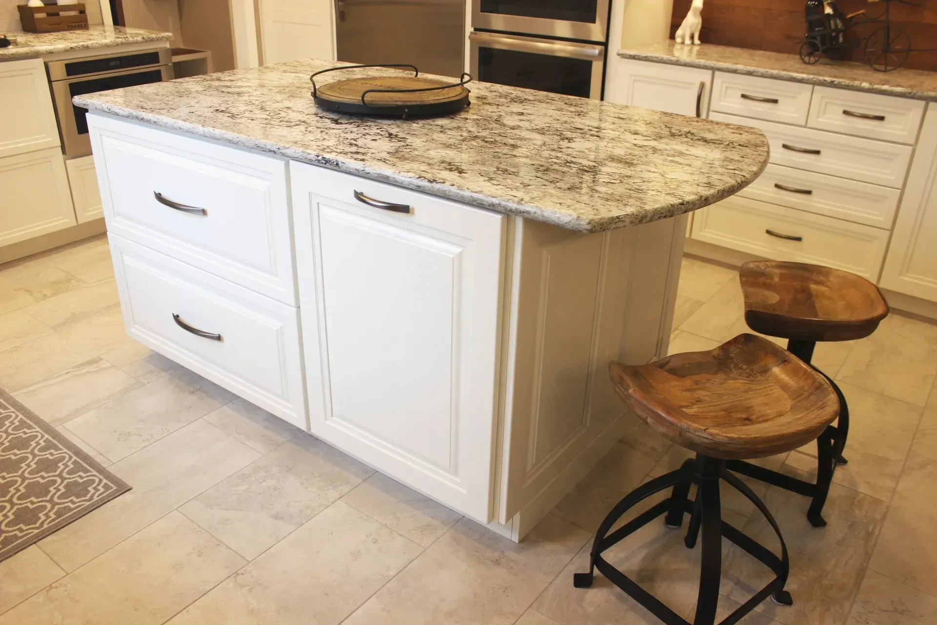 Kitchen island with granite countertop and two wooden stools in a bright, tiled kitchen In Bucks County PA
