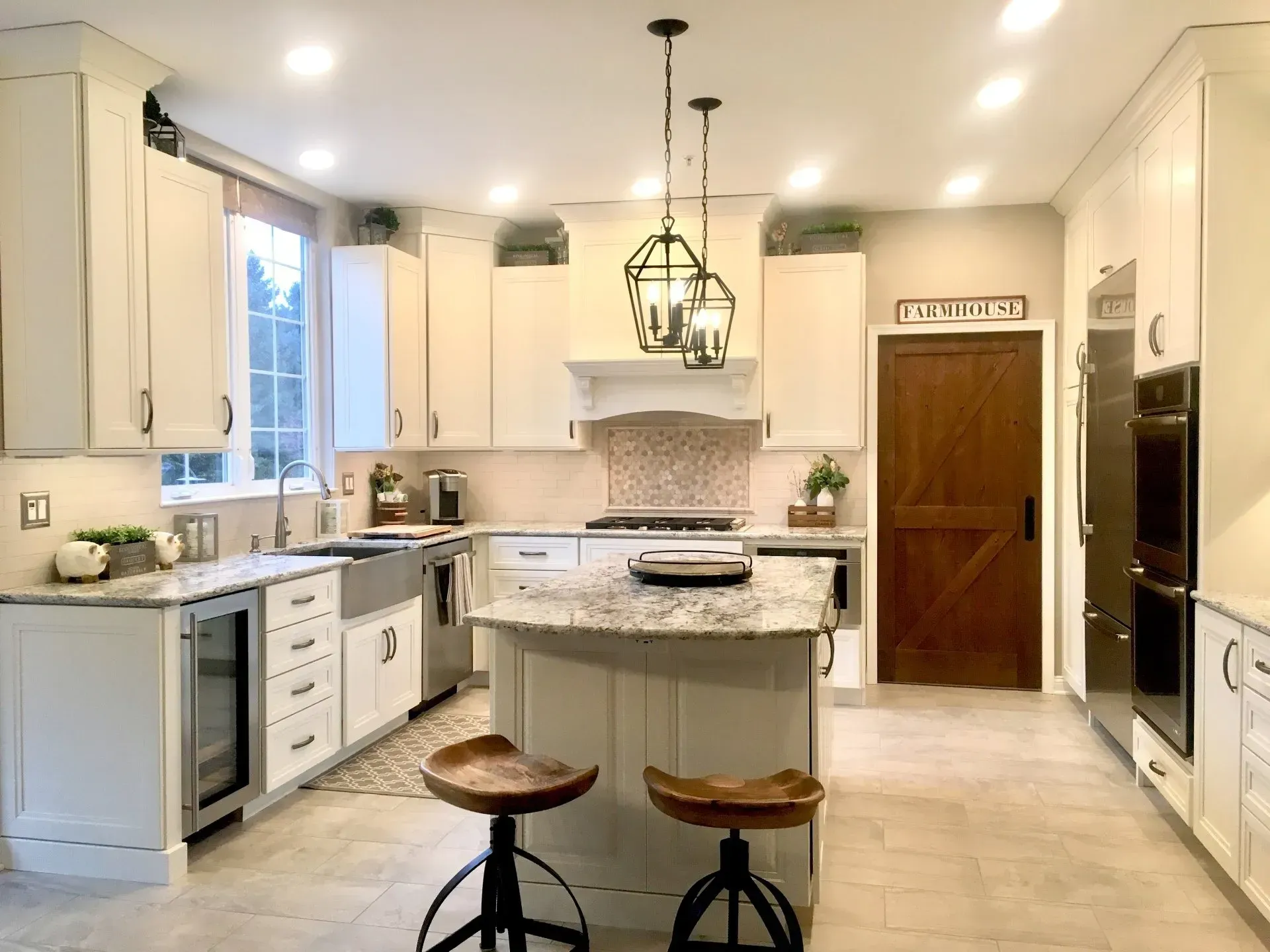 Bright modern kitchen with white cabinets, central island, stools, and wood front door In Bucks County PA