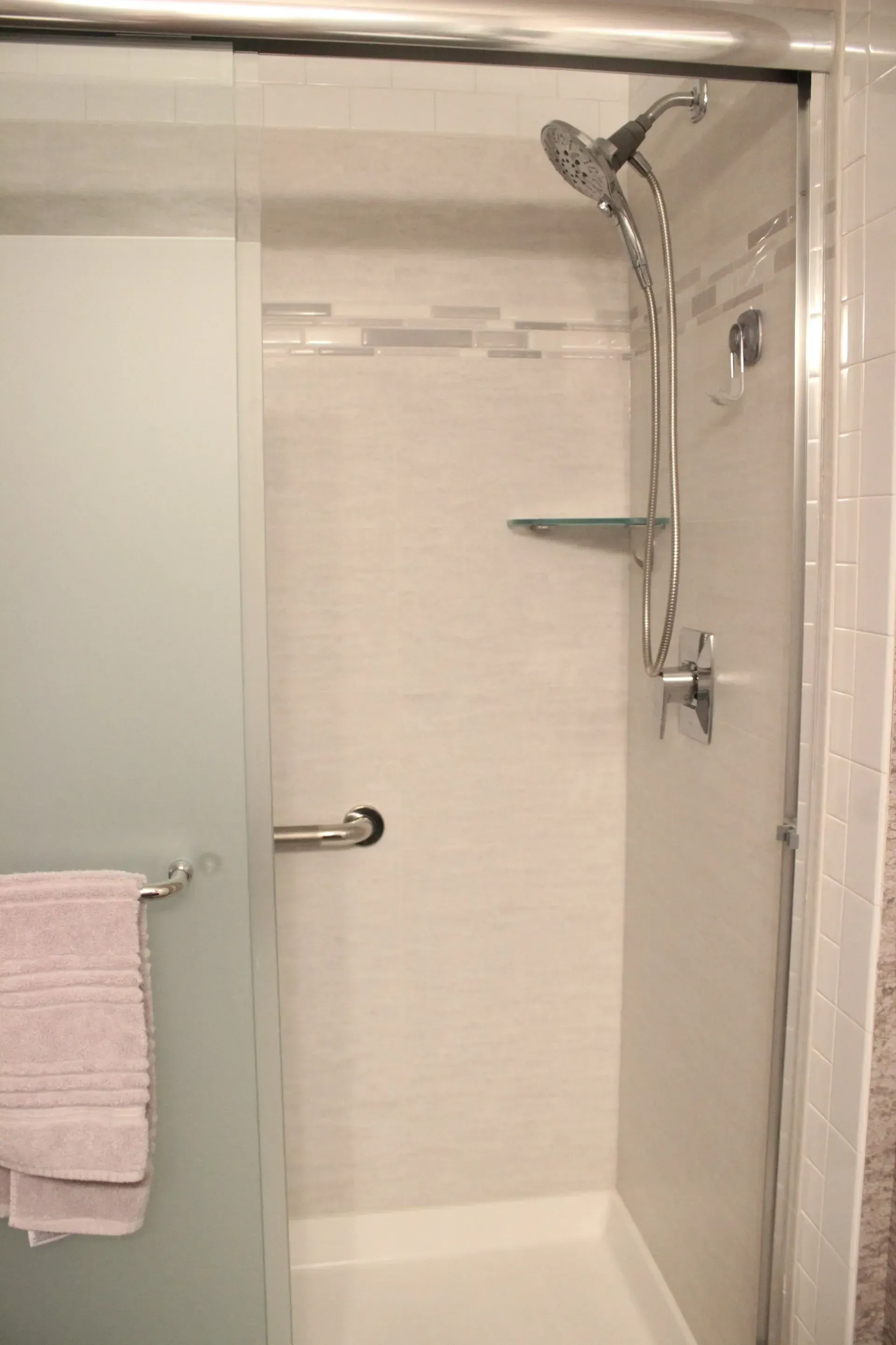 Bathroom shower with glass door, chrome showerhead, and towel rack with pink towel In Bucks County PA