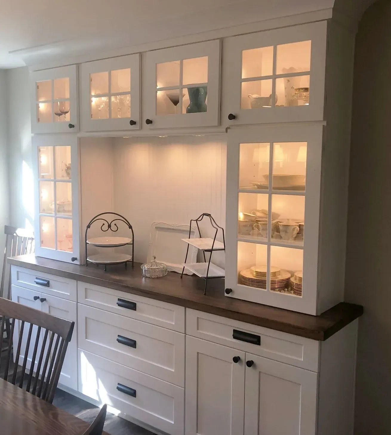 White kitchen hutch with glass cabinets, lit shelves, and dark wood countertop against a wall In Bucks County PA