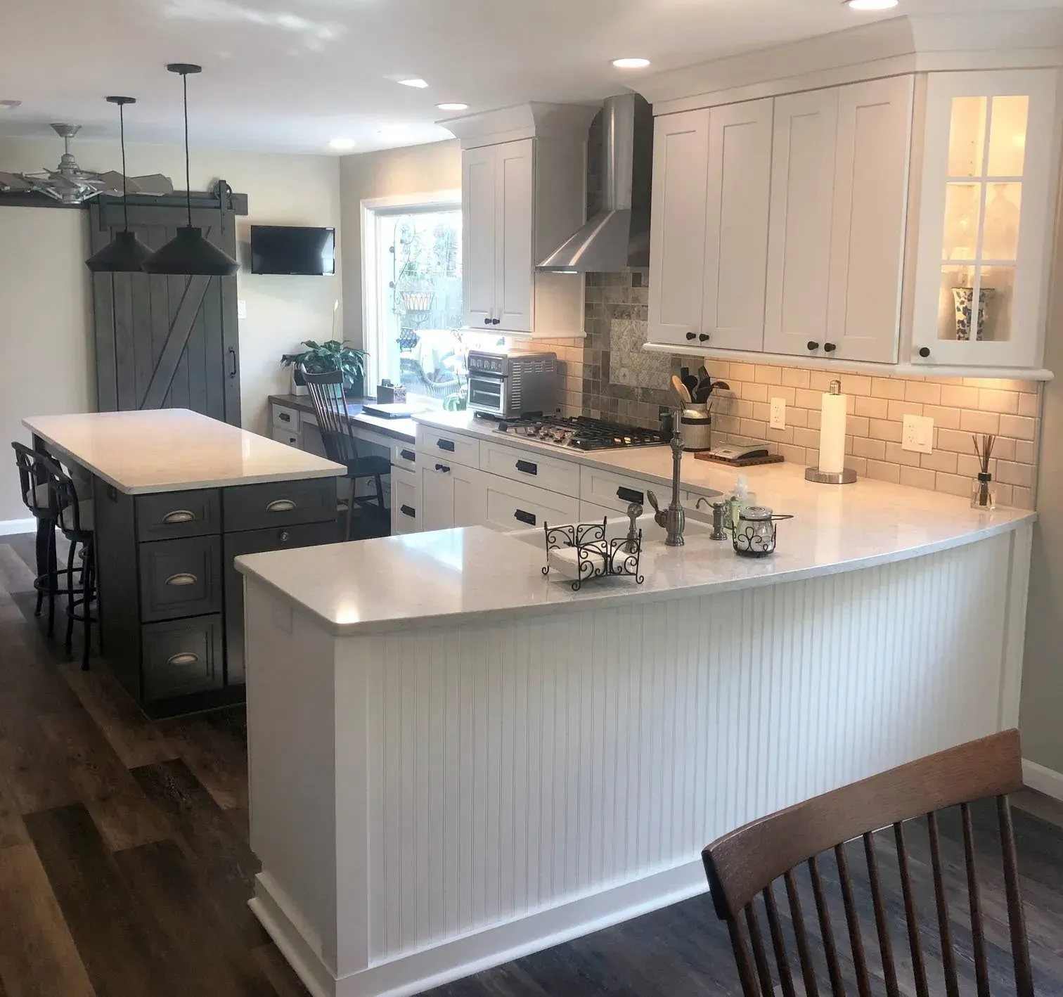 Bright modern kitchen with white cabinets, large island, and dark wood floor In Bucks County PA