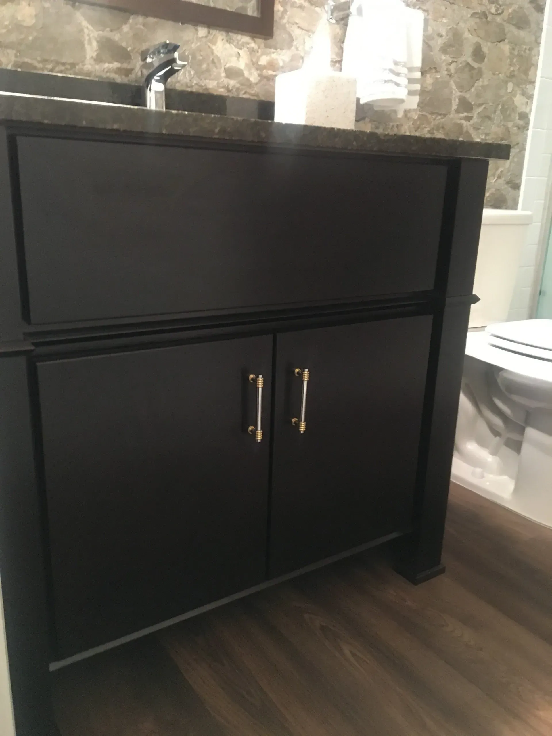 Black vanity cabinet with sink and stone countertop in a bathroom  In Bucks County PA