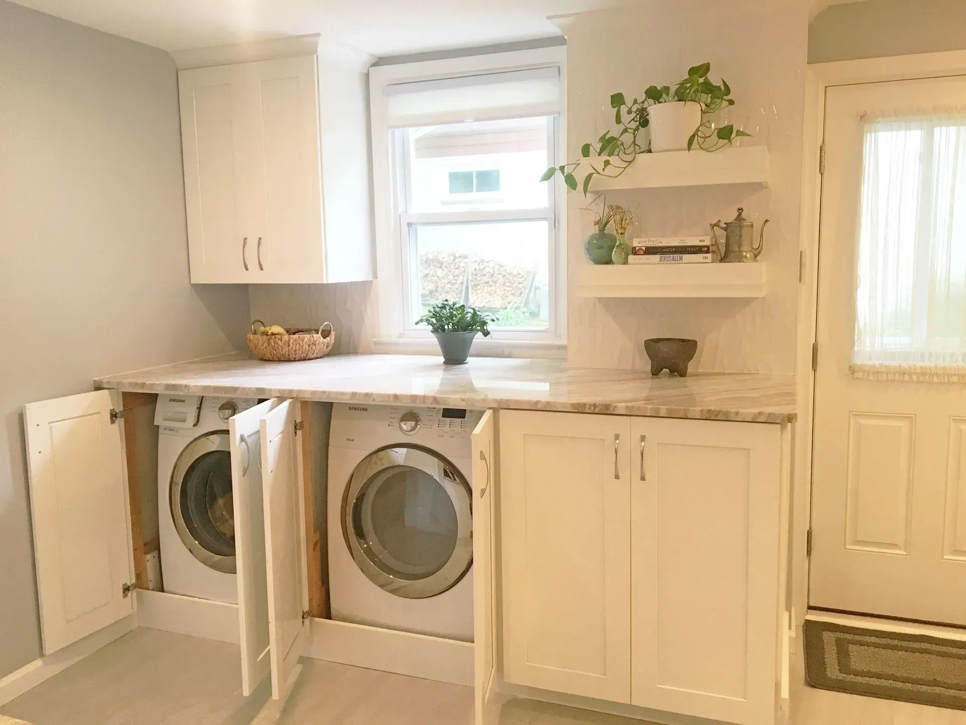 Bright laundry room with white washer and dryer, cabinets, sink, and window shelves in a cozy interior  In Bucks County PA