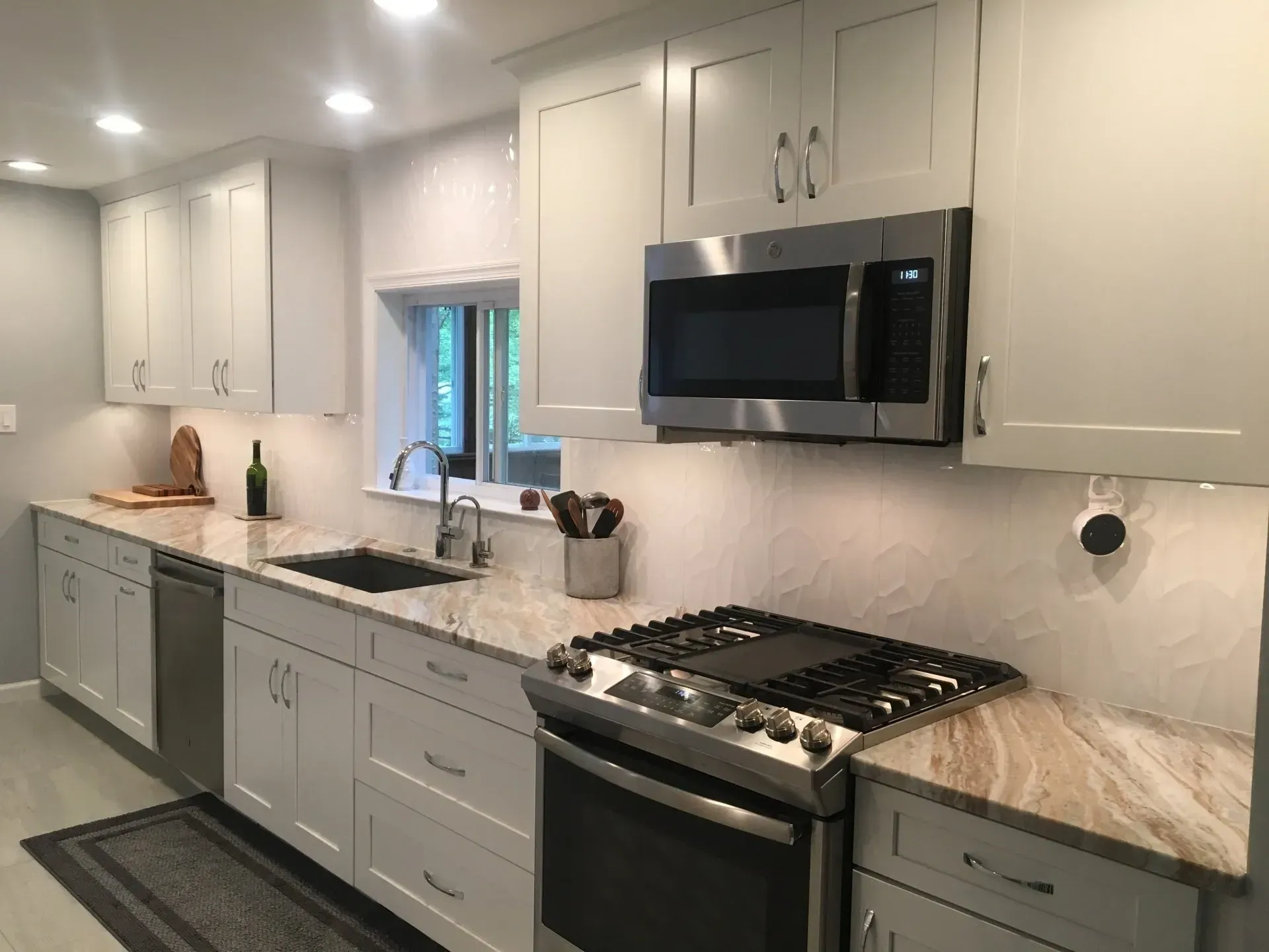 Bright modern kitchen with white cabinets, stainless appliances, and a dark runner rug In Bucks County PA