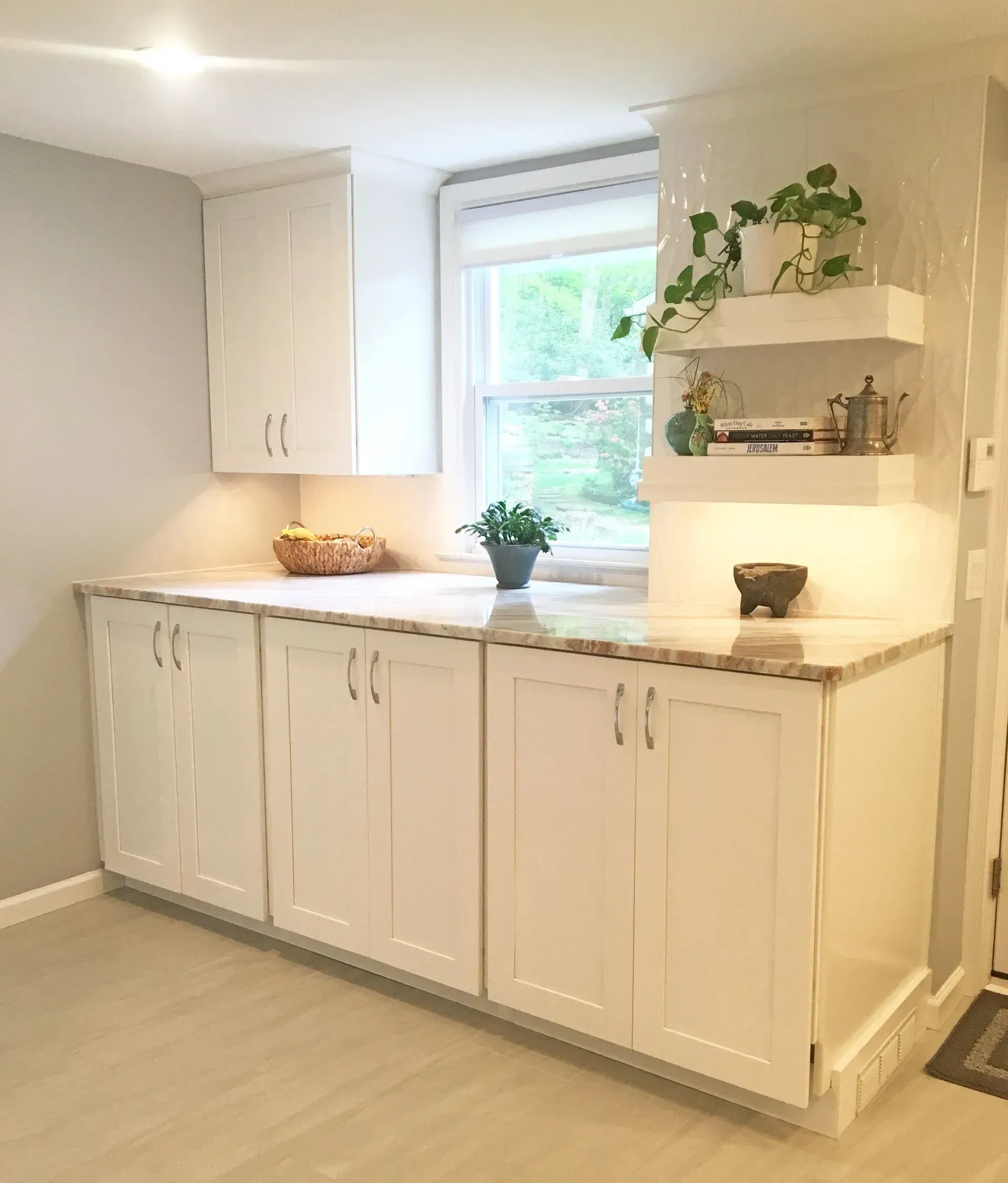 Bright white kitchen with cabinets, countertop, window, and potted plants In Bucks County PA