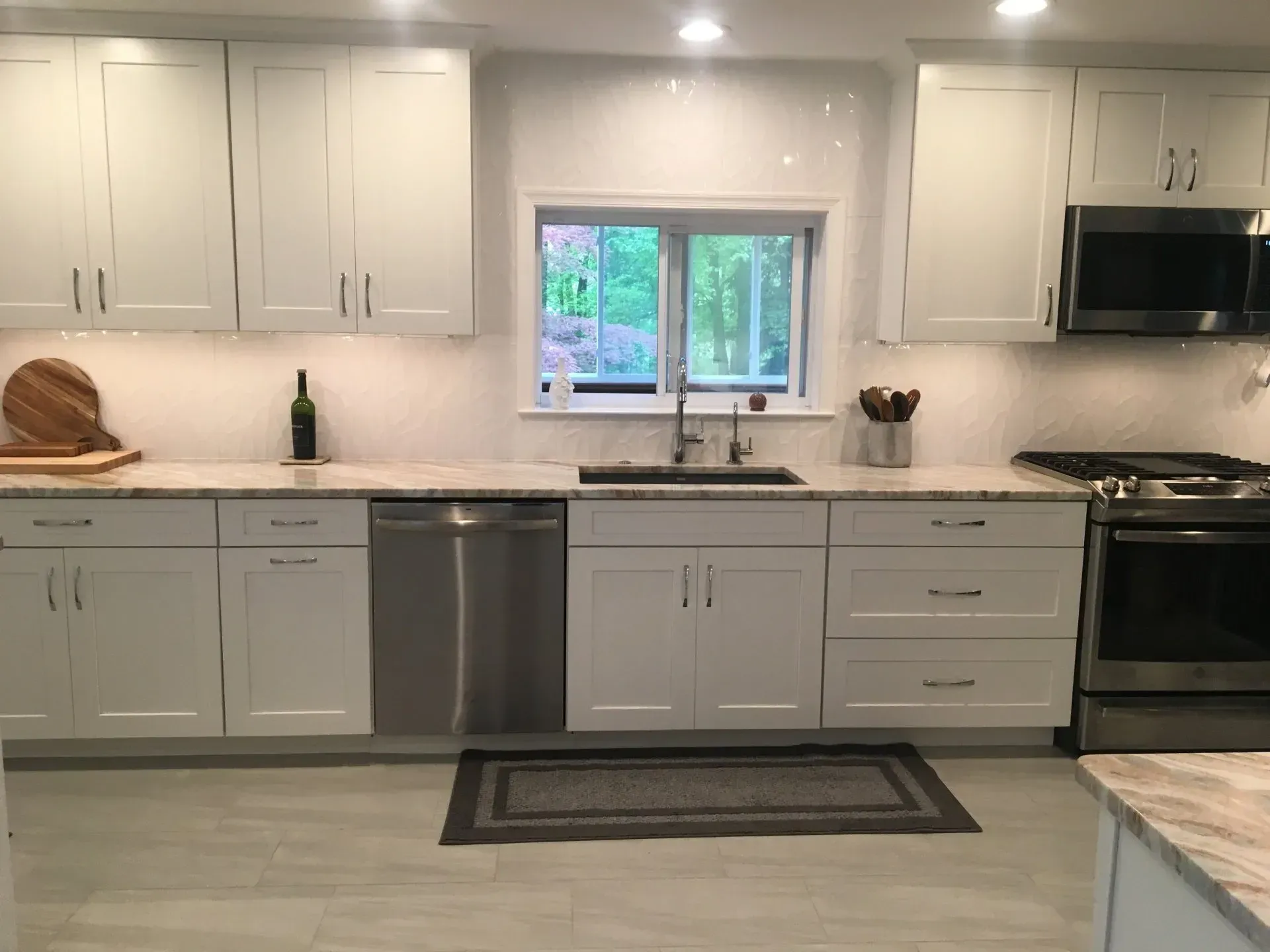Bright modern kitchen with white cabinets, stainless appliances, and a window over the sink In Bucks County PA