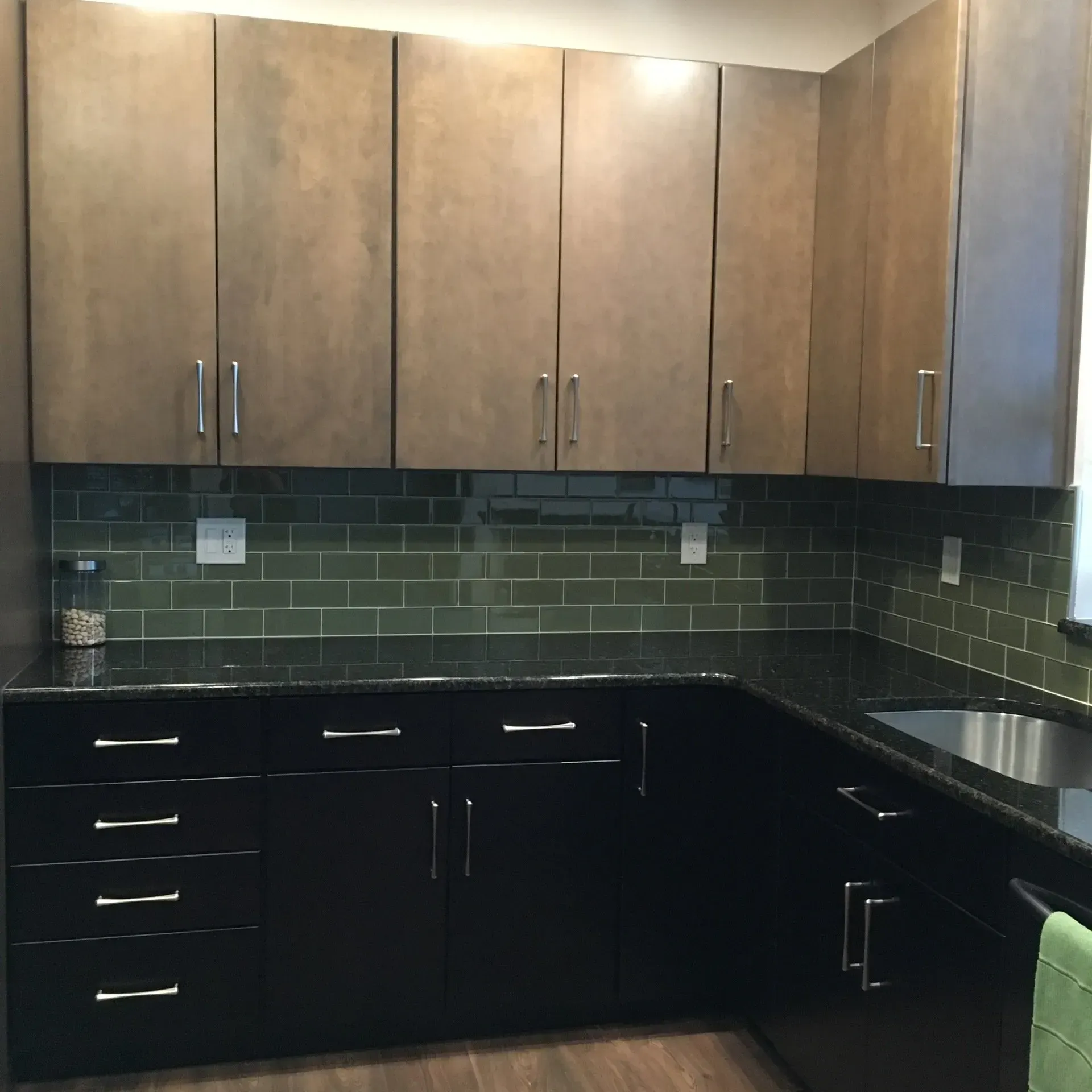 Modern kitchen with wood upper cabinets, black lower cabinets, green tile backsplash, and granite countertops  In Bucks County PA