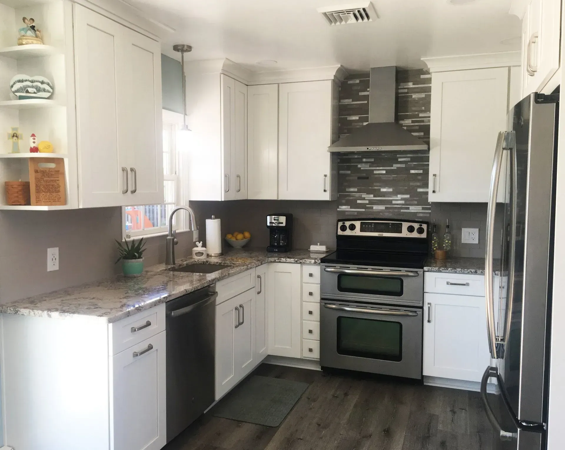 Modern kitchen with white cabinets, stainless steel appliances, granite counters, and dark wood flooring In Bucks County PA