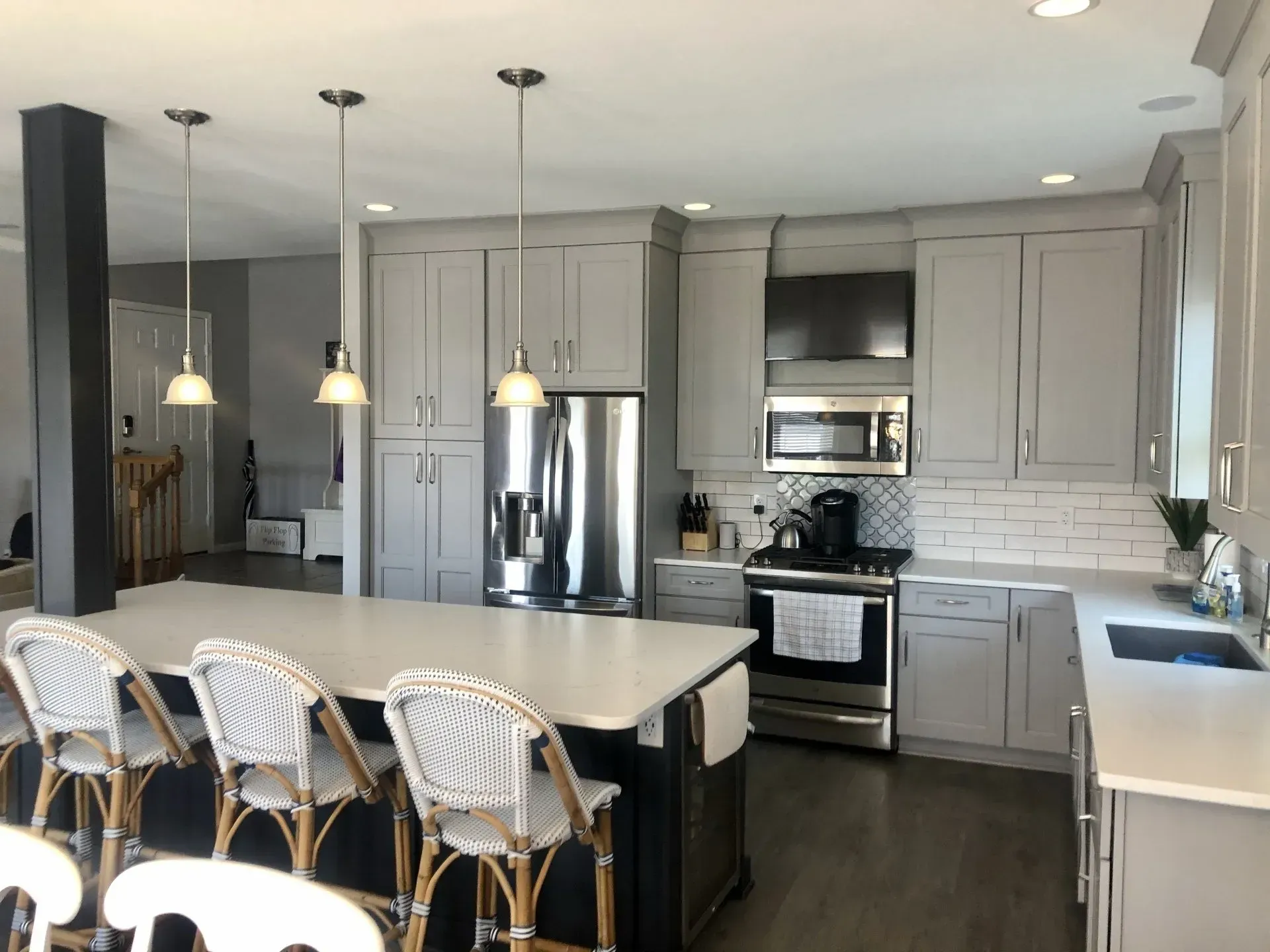 Modern kitchen with gray cabinets, island seating, stainless appliances, and pendant lights