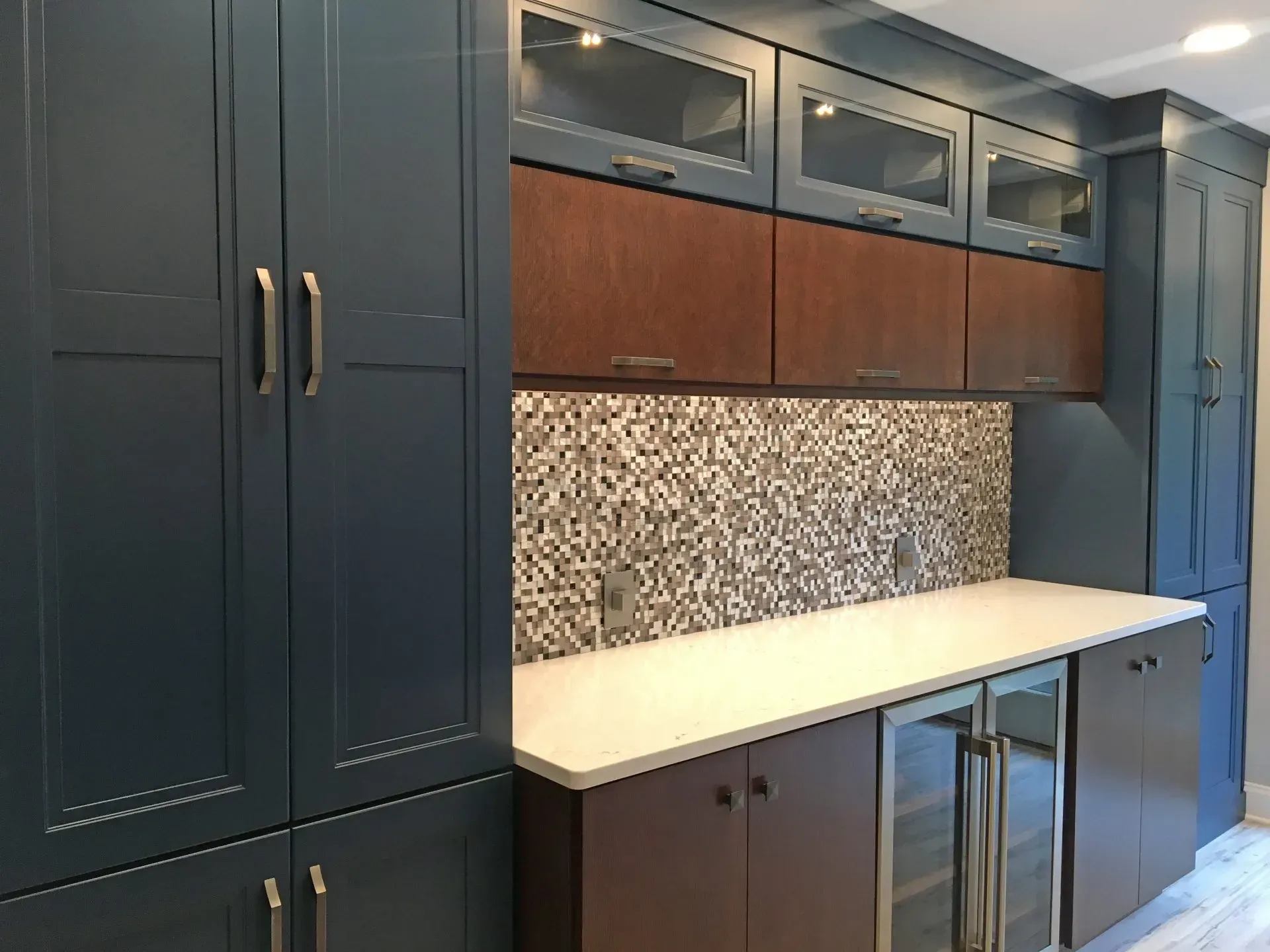Dark navy cabinets with wood accents, patterned backsplash, and a light countertop in a modern kitchen  In Bucks County PA