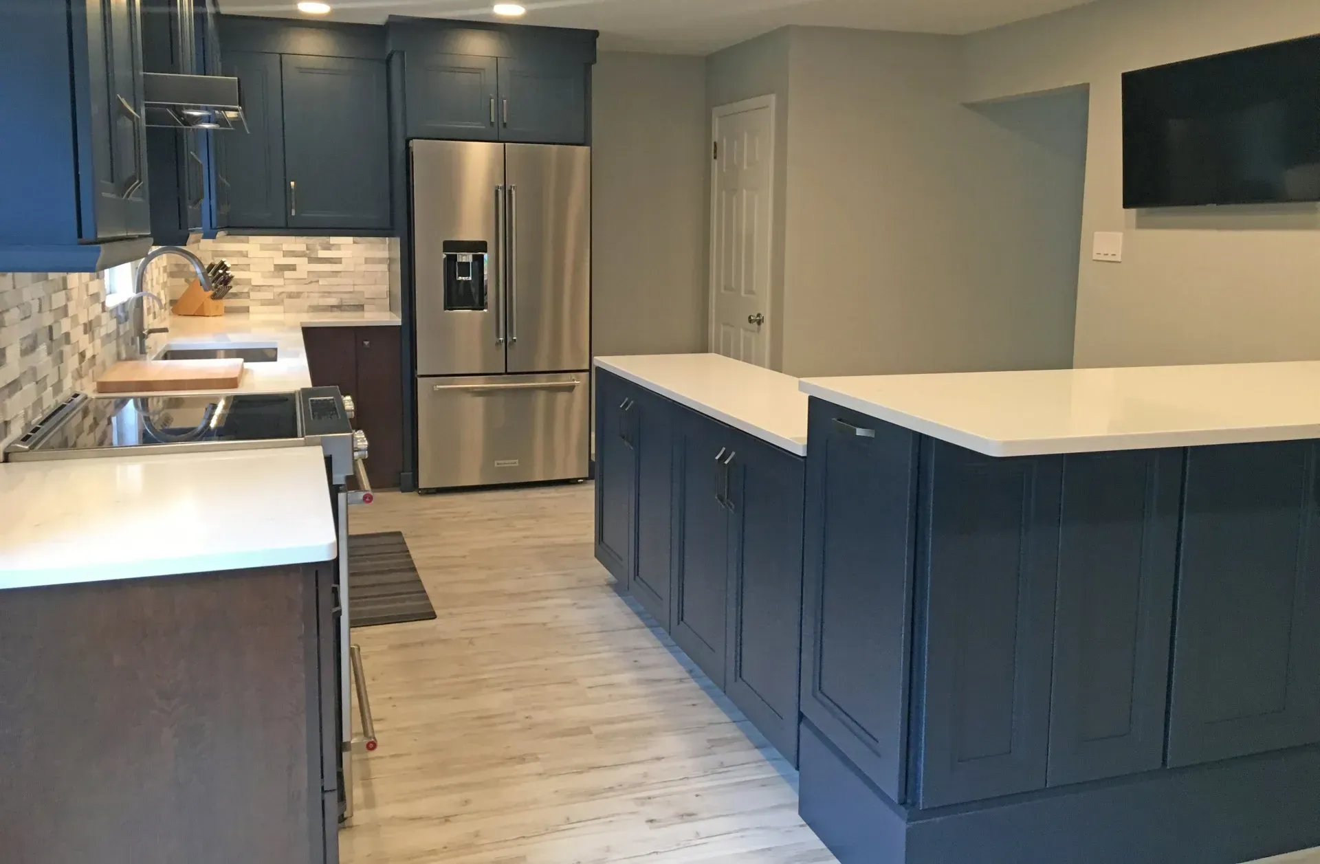 Modern kitchen with dark blue cabinets, white countertops, stainless fridge, and a central island  In Bucks County PA