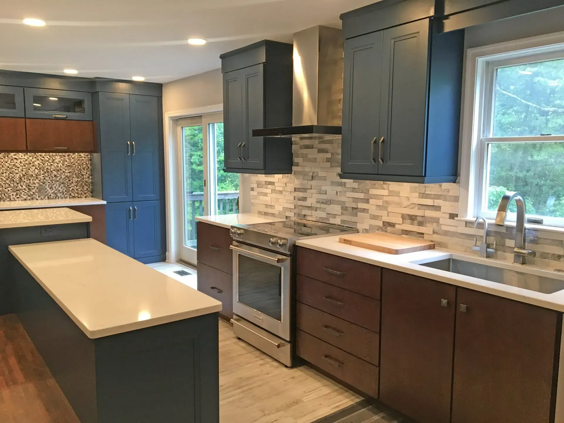 Modern kitchen with blue and brown cabinets, stainless steel appliances, and a white island countertop  In Bucks County PA