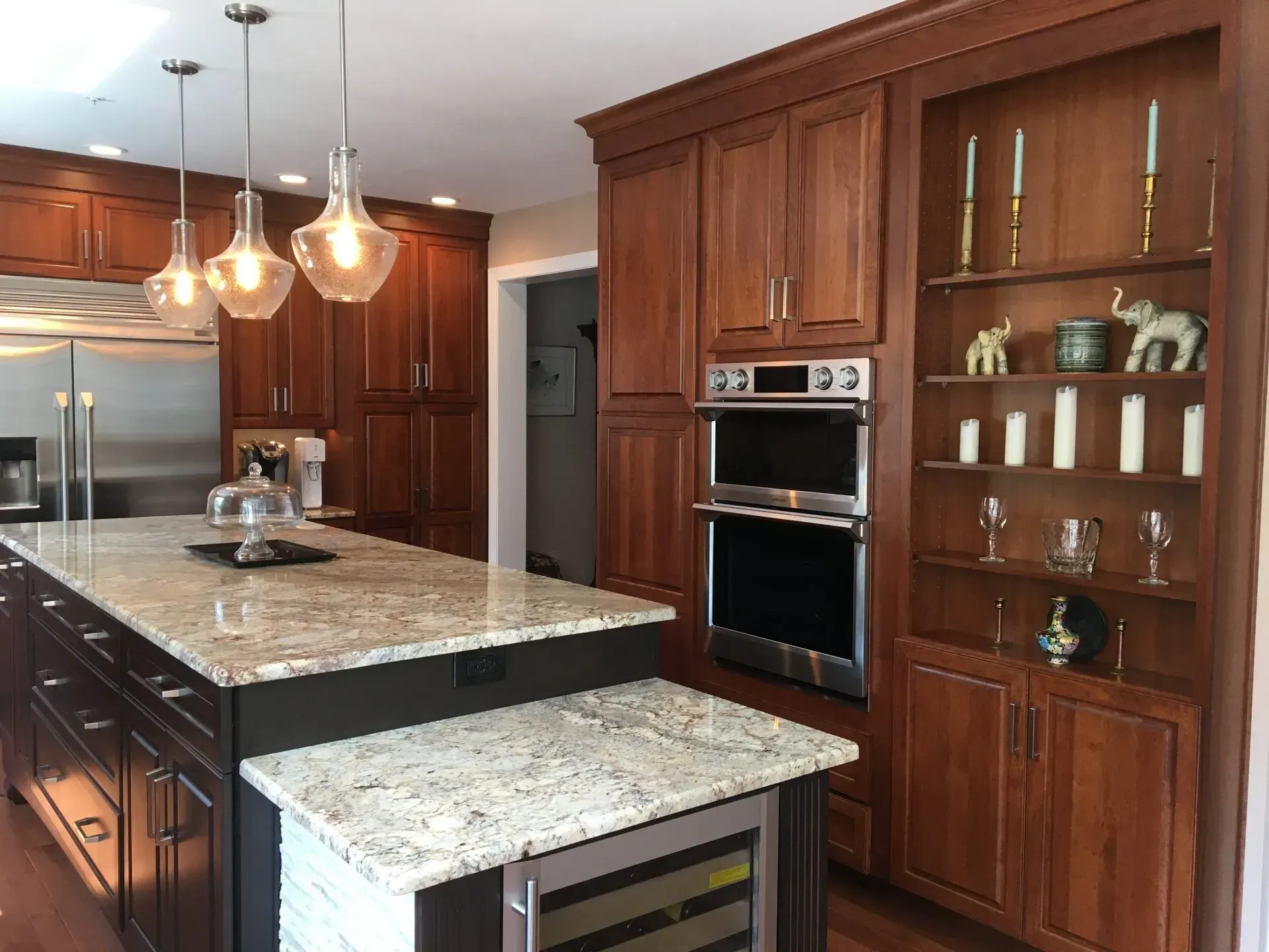 Modern kitchen with dark wood cabinets, granite island, pendant lights, and built-in oven In Bucks Country PA