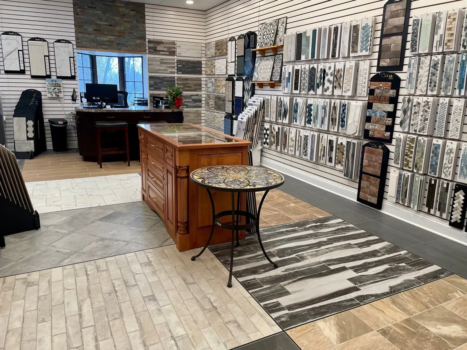 Interior of a tile showroom with display walls, a wooden counter, and patterned rugs on the floor  In Bucks County PA