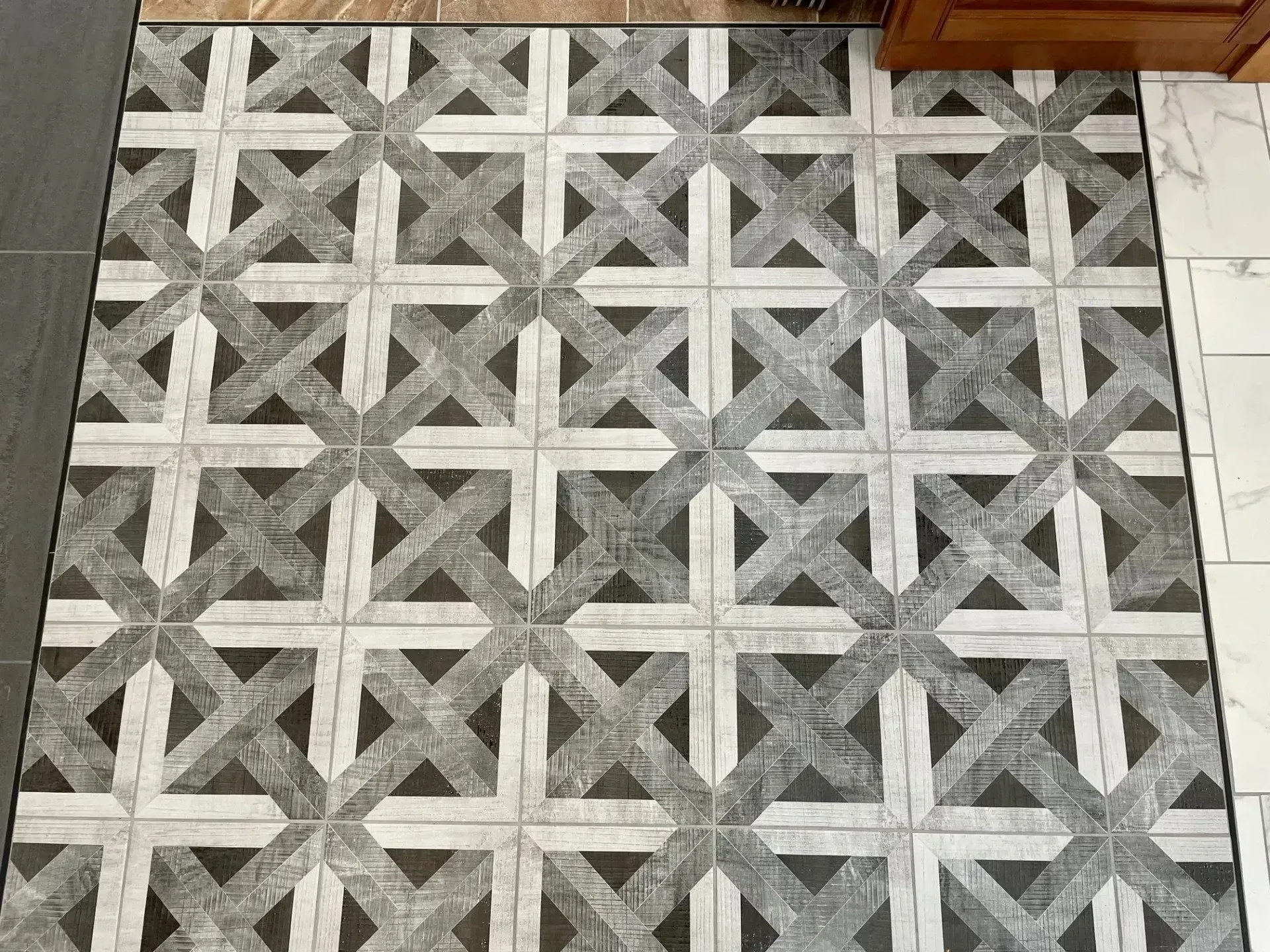 Gray patterned tile floor with a geometric lattice design and a strip of white tiles along the right edge  In Bucks County PA