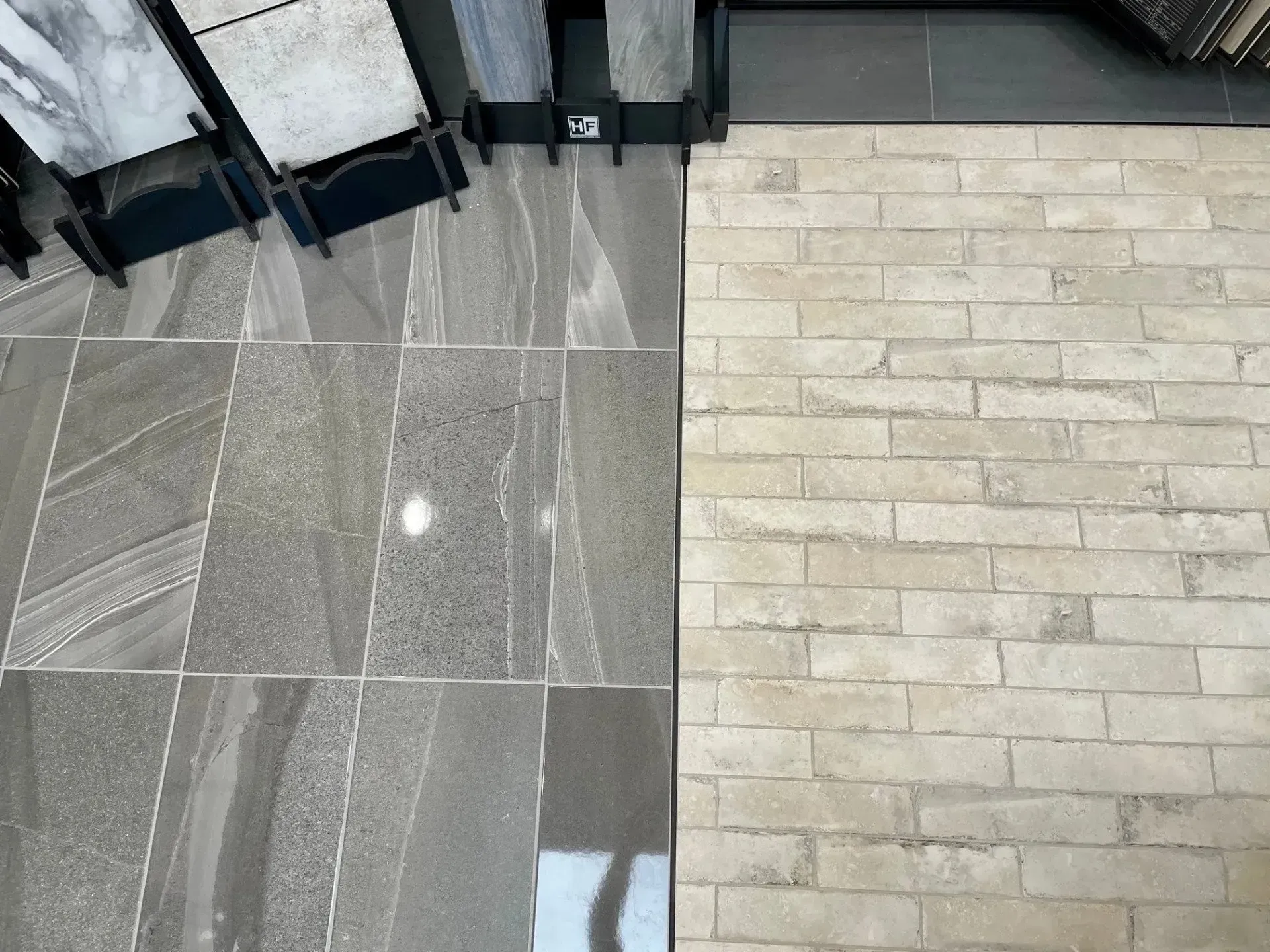 Indoor floor transition with gray stone tiles beside beige brick pavers near chairs and a table  In Bucks County PA