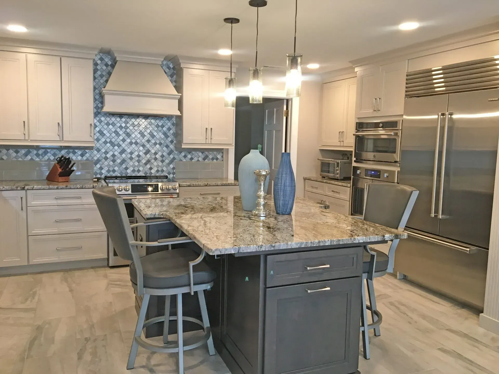 Modern kitchen with large island, granite countertop, white cabinets, and stainless steel appliances in Bucks County PA
