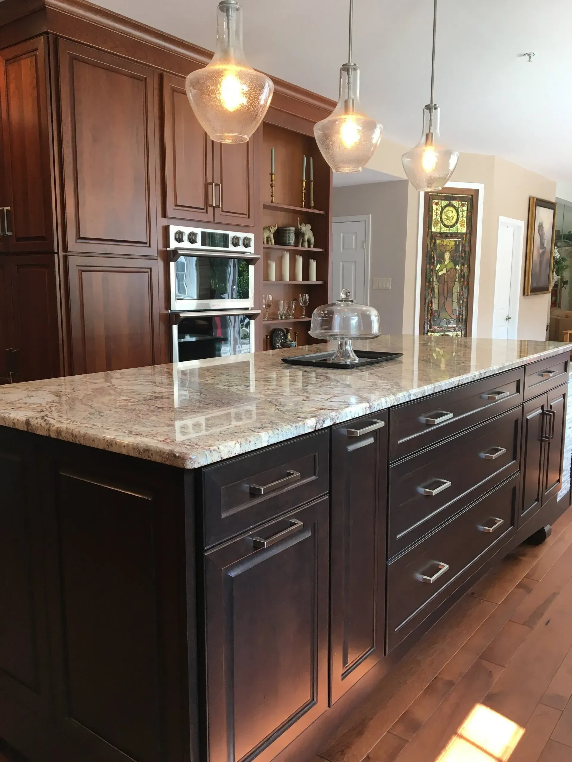Modern kitchen with dark wood cabinets, granite island, pendant lights, and built-in oven In Bucks Country PA