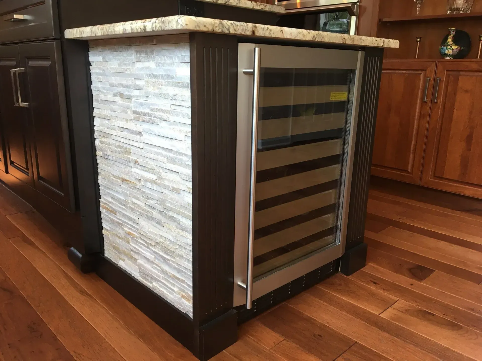 Compact wine cooler with glass door and stone paneling built into a kitchen island In Bucks Country PA