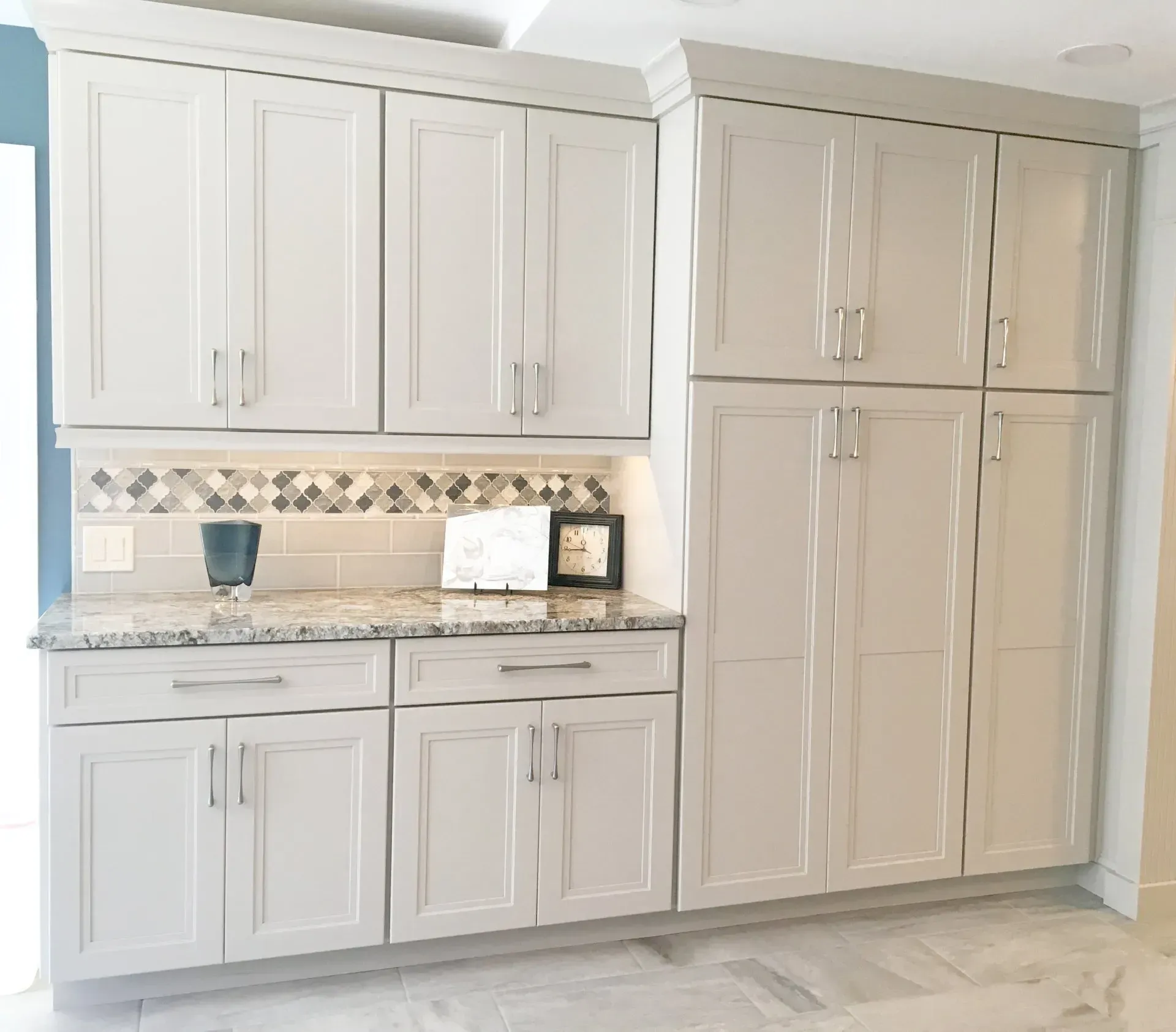 White kitchen cabinetry with granite countertop and decorative tile backsplash in Bucks County PA
