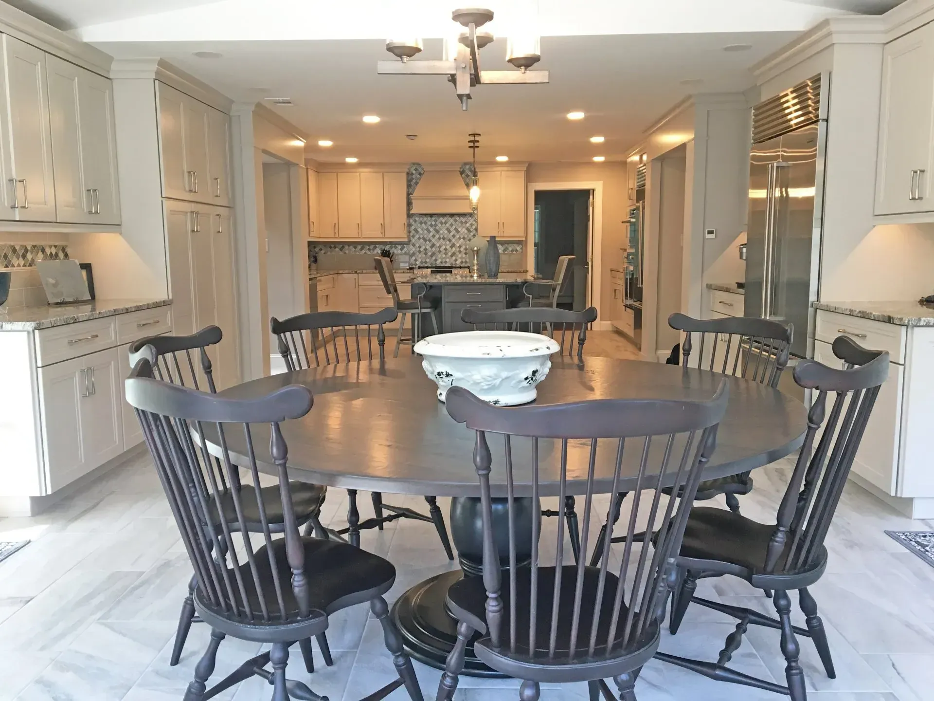 Bright kitchen with a round wooden dining table, black chairs, and an open view to a living area in Bucks County PA