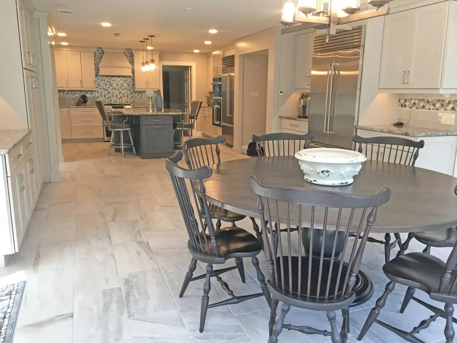 Bright open kitchen and dining area with a round table, chairs, white cabinets, and light wood flooring  in Bucks County PA