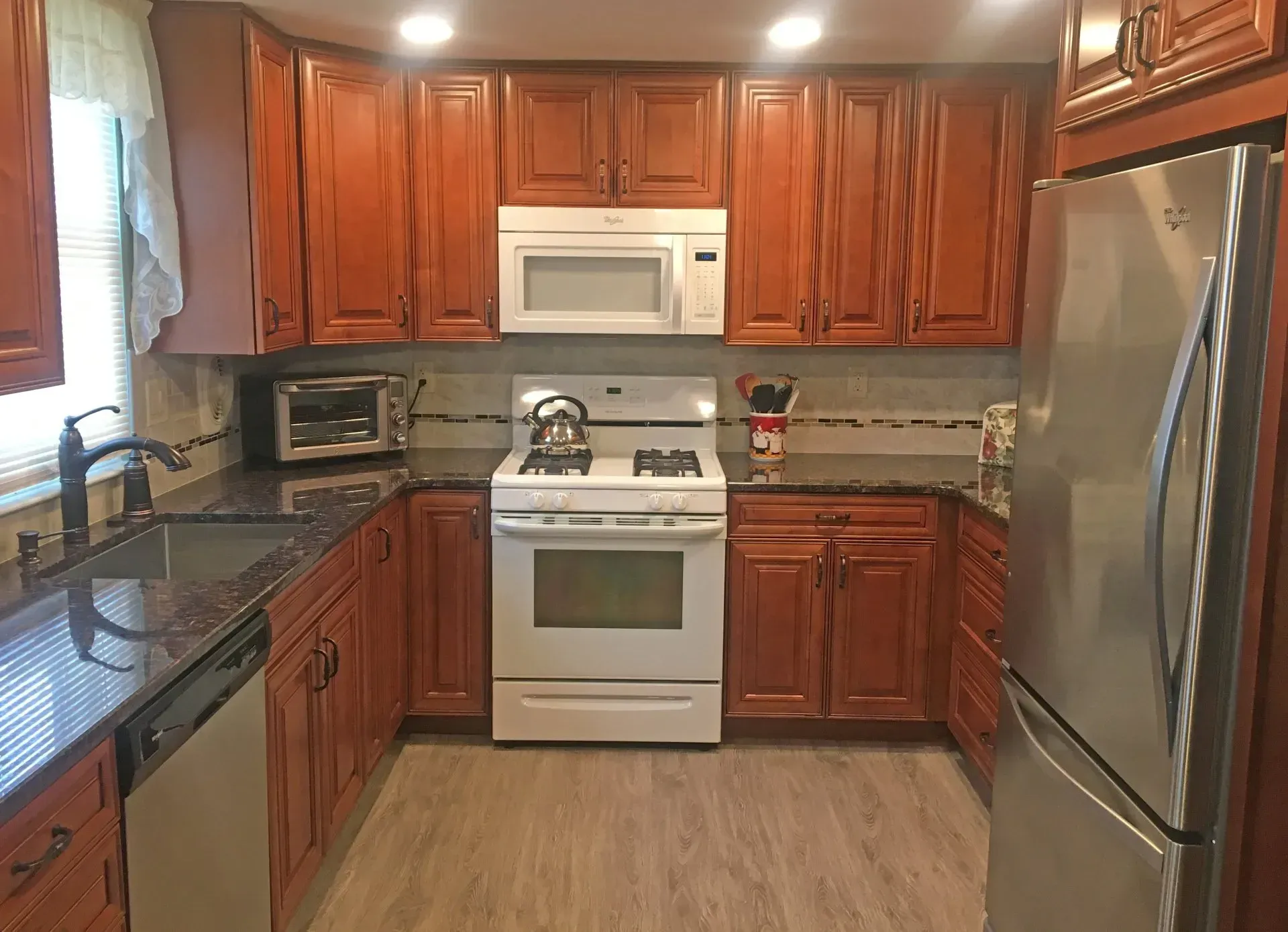 Compact kitchen with wood cabinets, white stove and microwave, and stainless-steel refrigerator In Bucks Country PA