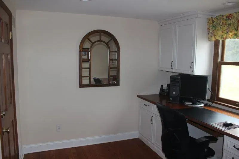 Home office with desk, computer, chair, window, and wall mirror on a white wall in Bucks County PA