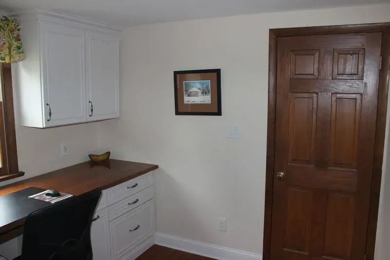 Small home office with a desk, white cabinets, framed picture, and a wooden door in Bucks County PA