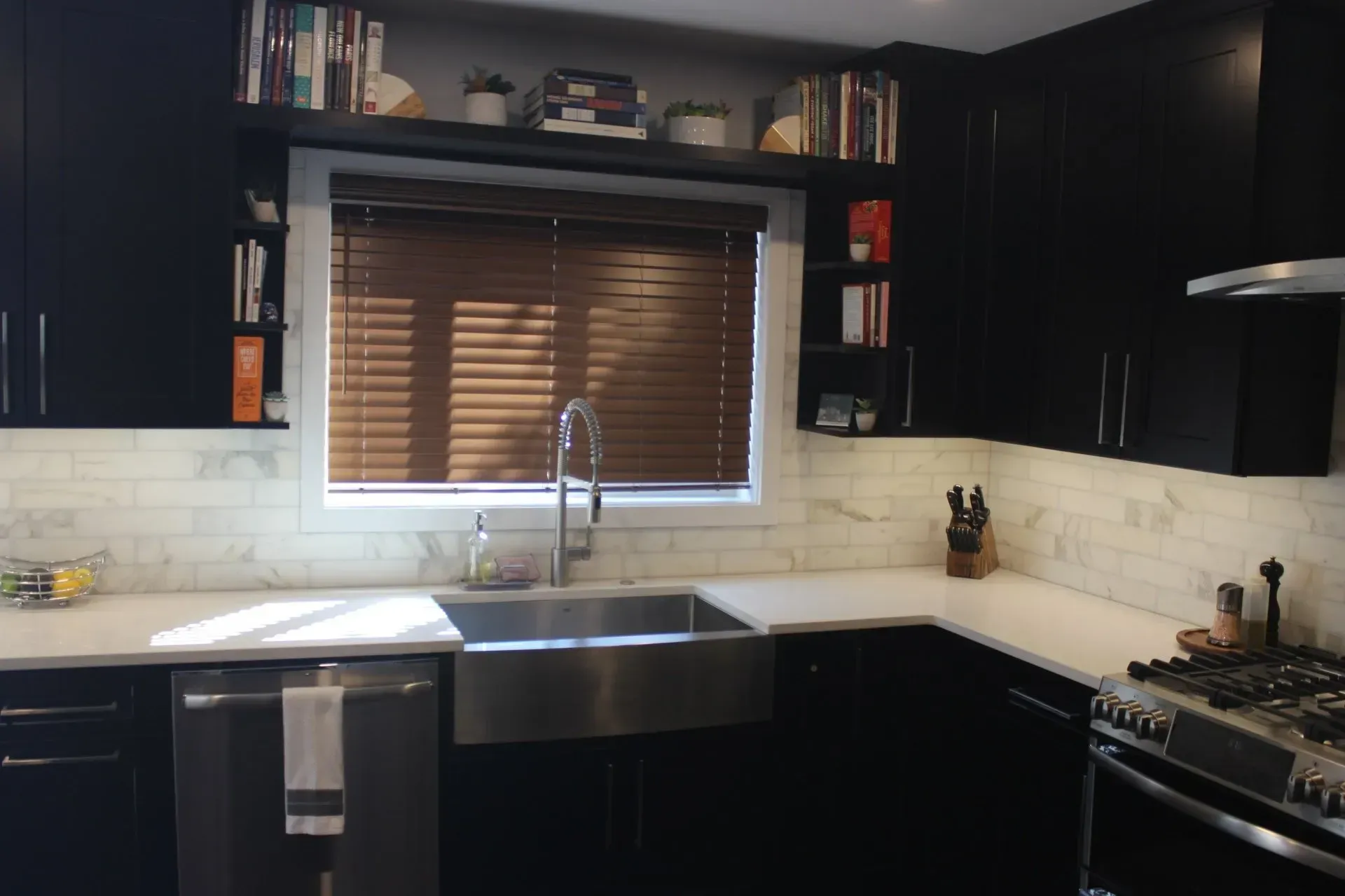 Modern kitchen with dark cabinets, a stainless sink under a window, and a gas stove on the right In Bucks Country PA