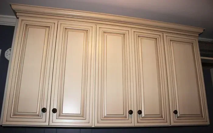 Cream-colored kitchen wall cabinets with raised panel doors and black knobs  In Bucks County PA
