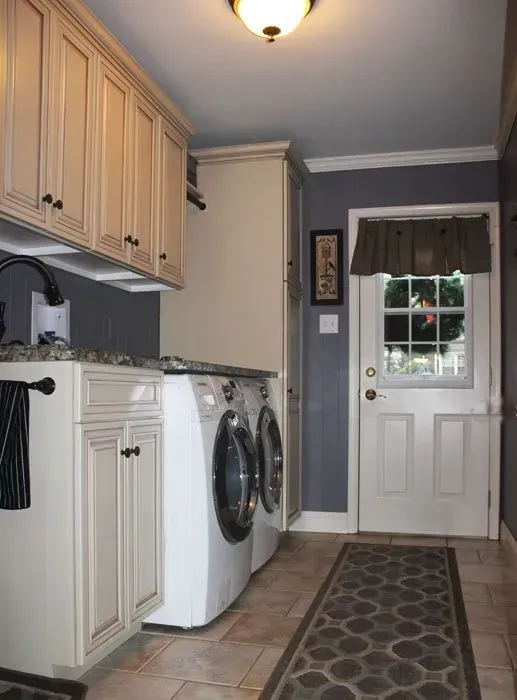 Laundry room with washer and dryer, white cabinets, and a door at the end of a narrow hallway  In Bucks County PA