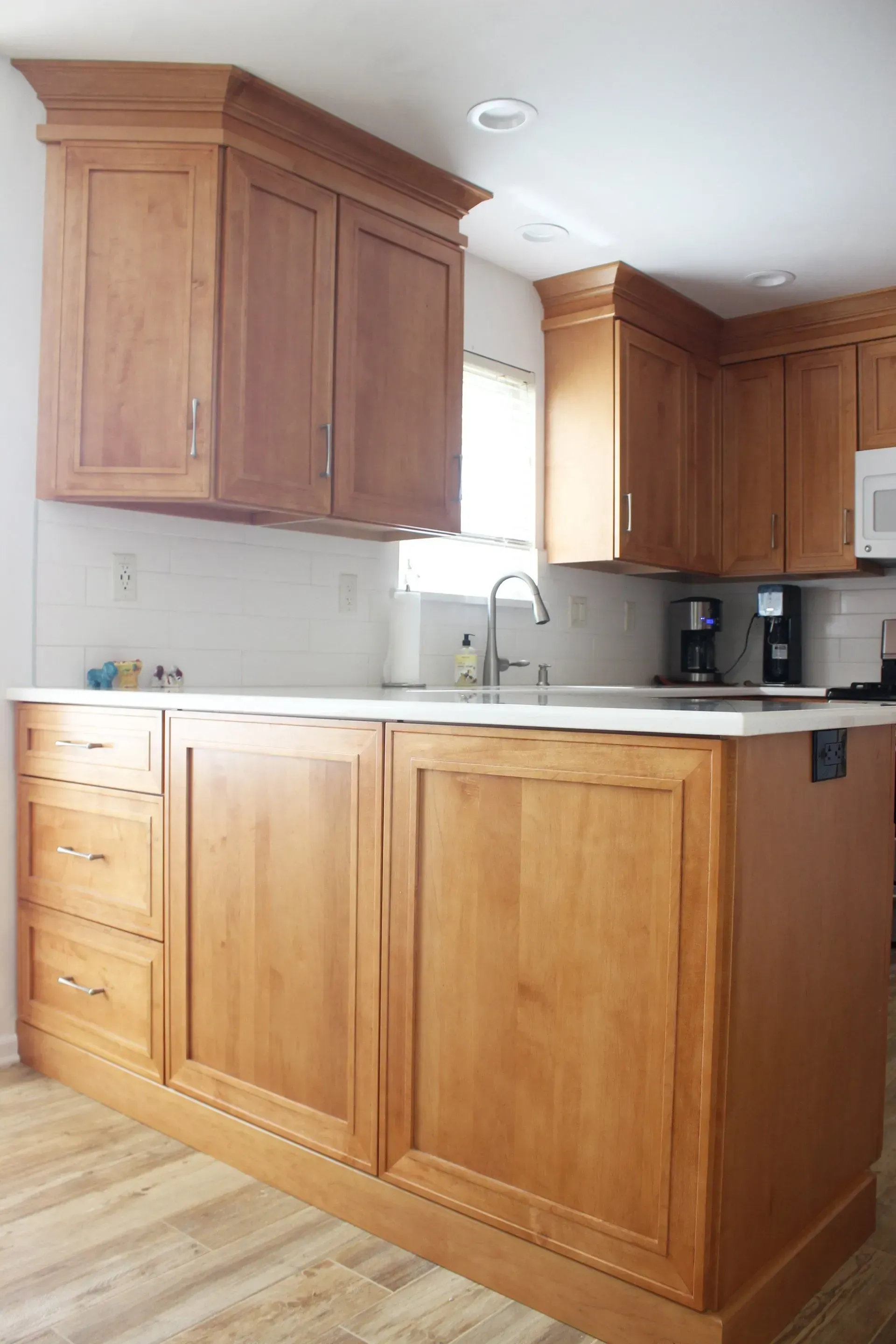 Kitchen with light wood cabinets, white countertops, and a sink under a window  In Bucks County PA