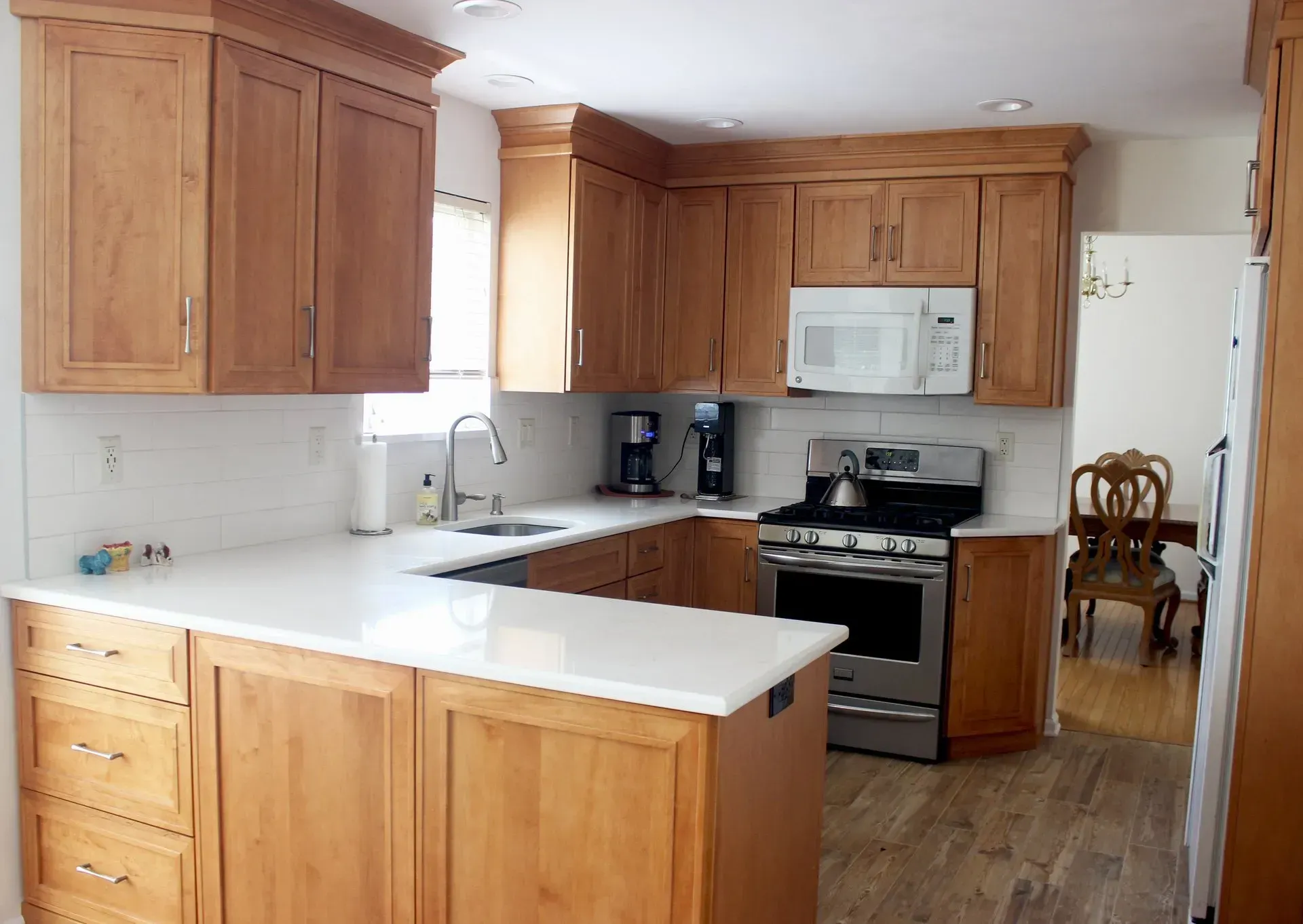 Bright kitchen with wooden cabinets, white countertops, and stainless steel stove and microwave In Bucks Country PA
