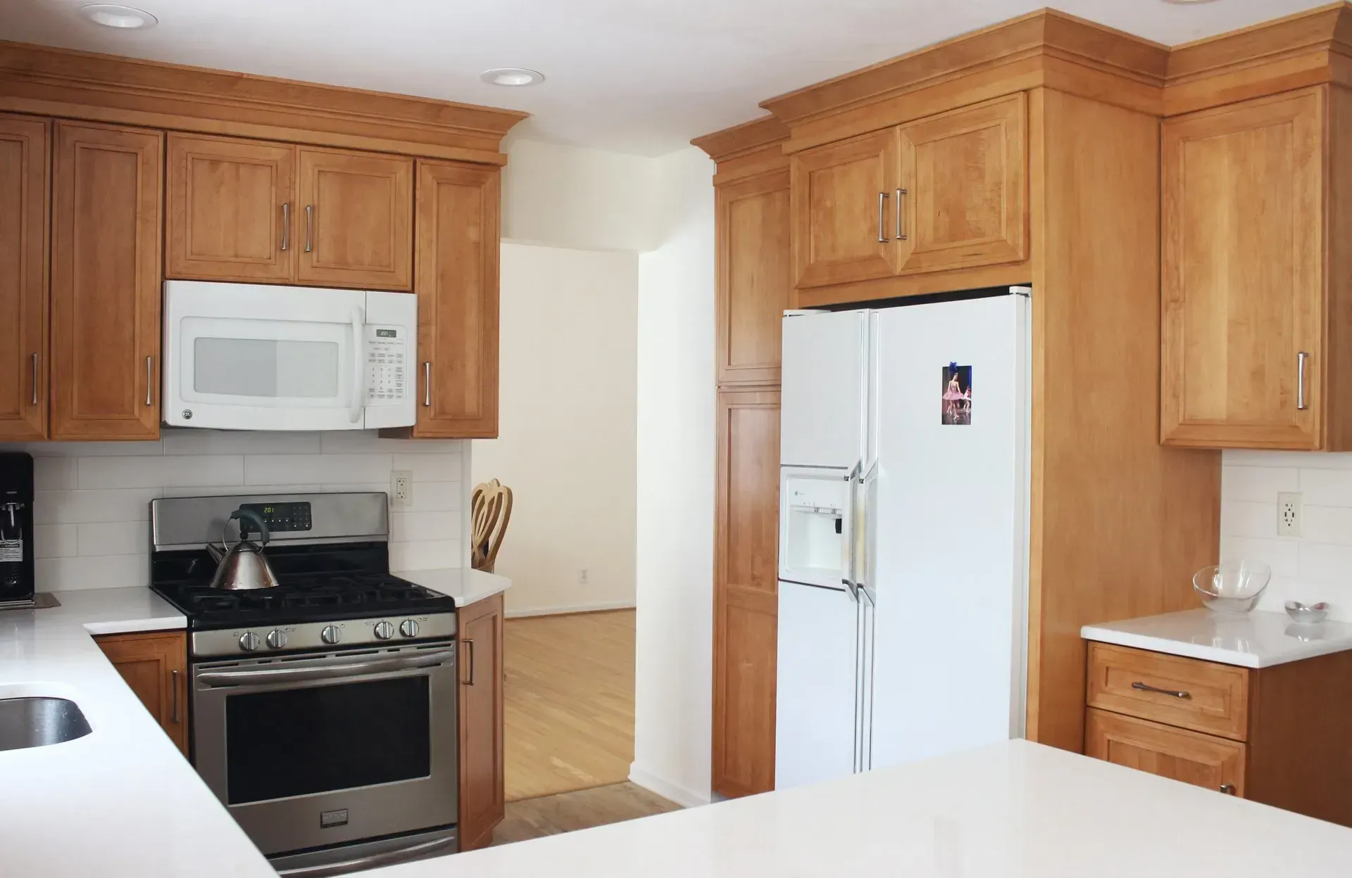 Bright kitchen with wooden cabinets, white appliances, and a black stove under a microwave  In Bucks County PA