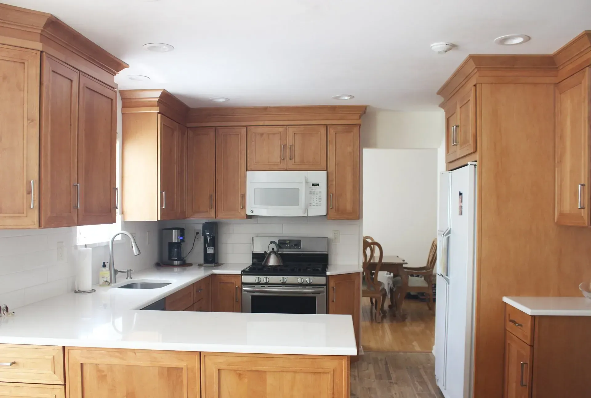 Bright kitchen with oak cabinets, white countertops, and a dining table in the background  In Bucks County PA