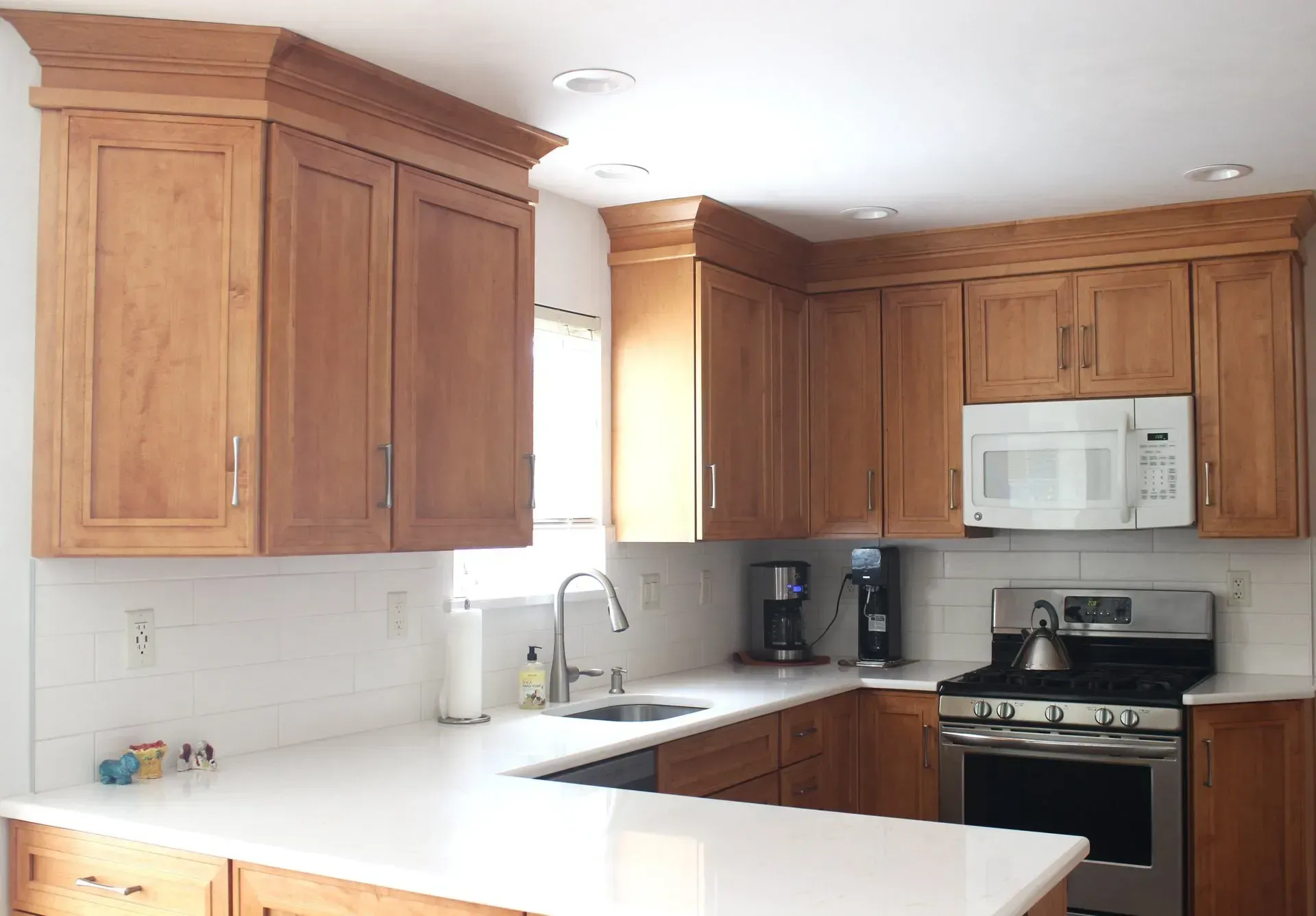Bright kitchen with wooden cabinets, white countertops, and a stainless-steel stove and microwave  In Bucks County PA