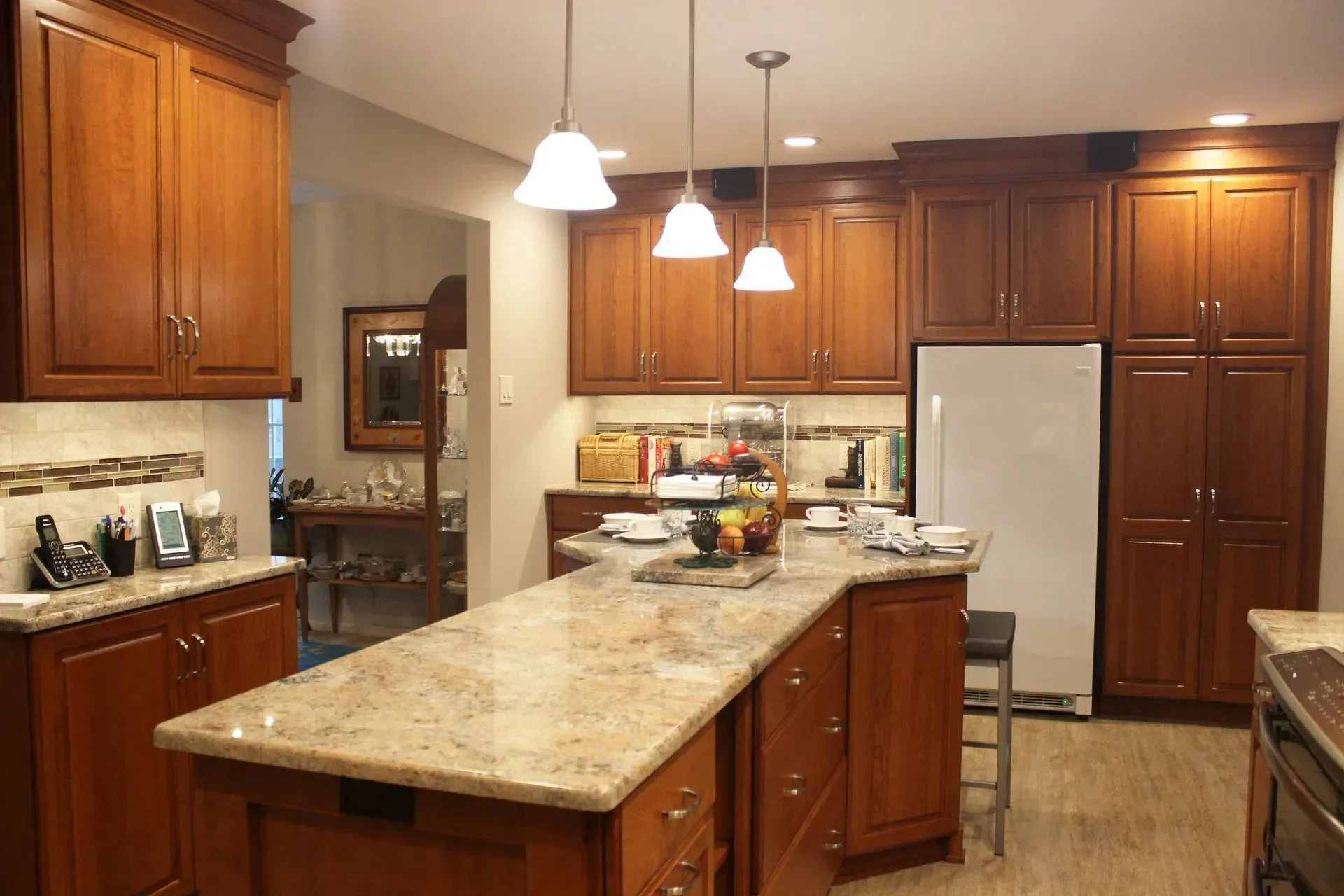 Spacious kitchen with wood cabinets, granite island, pendant lights, and stainless steel refrigerator In Bucks County PA