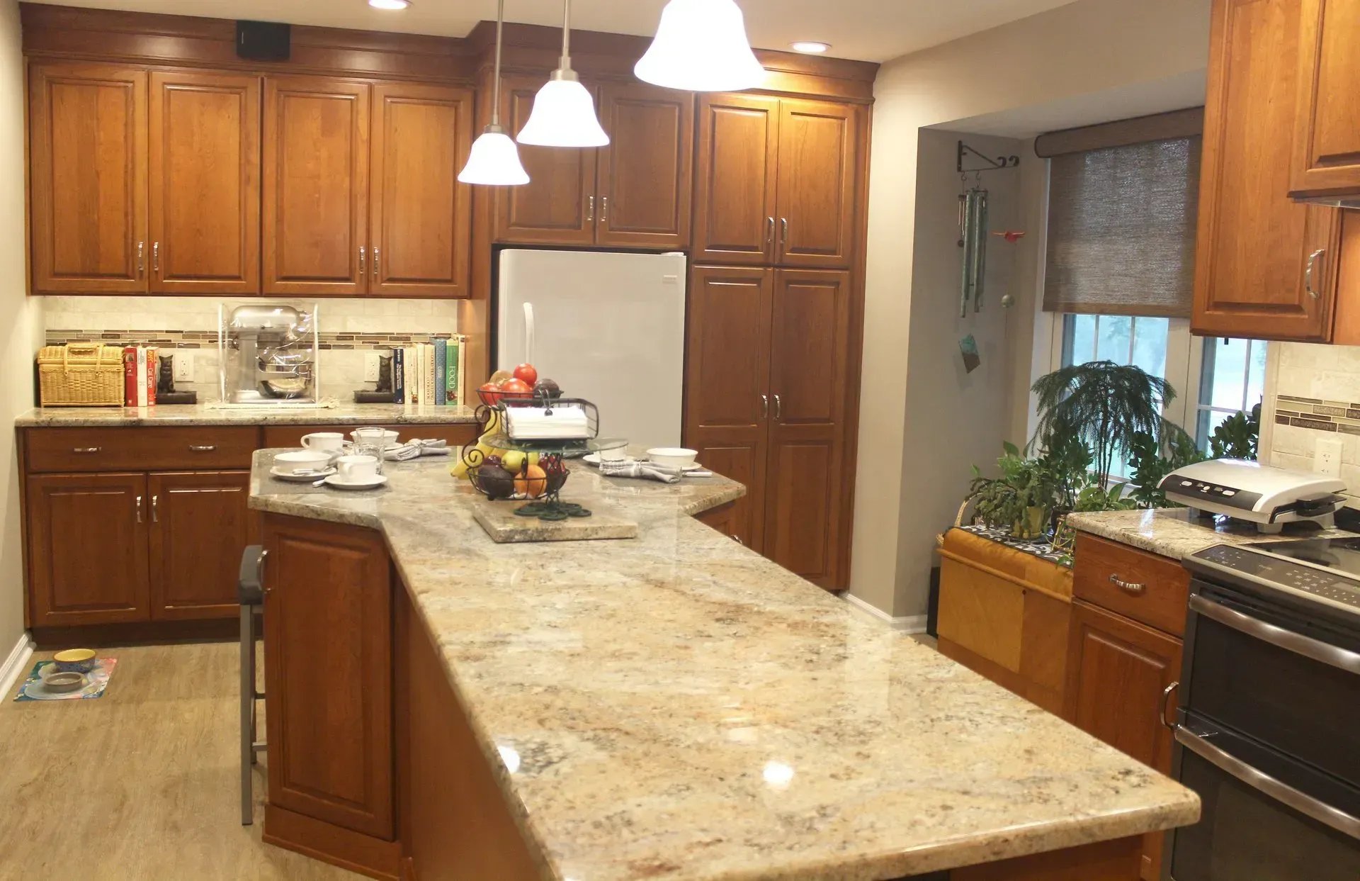 Spacious kitchen with granite island, wooden cabinets, pendant lights, and a window over the sink In Bucks Country PA