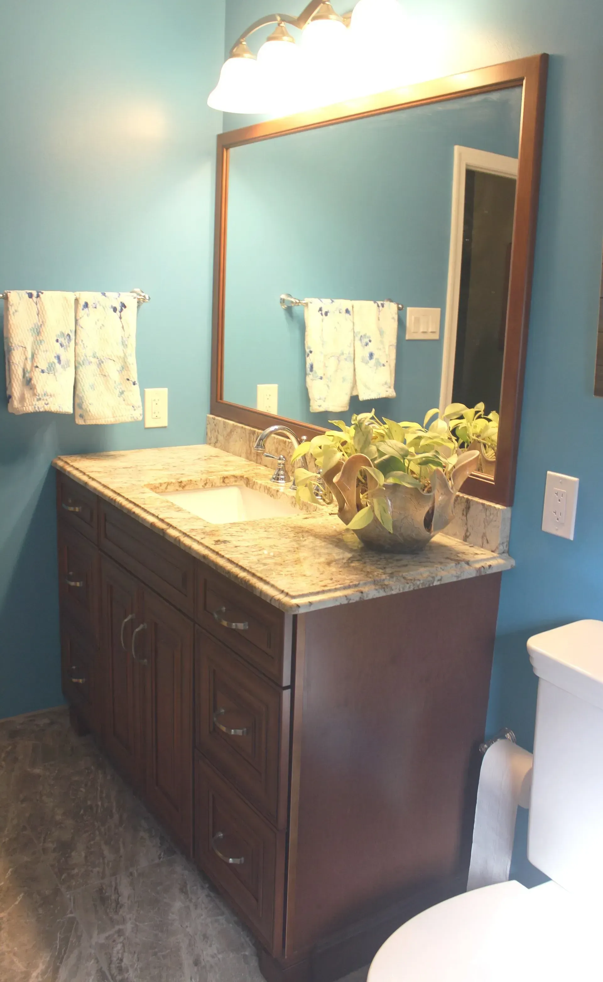 Bathroom vanity with dark wood cabinet, granite countertop, large mirror, and blue walls  In Bucks County PA