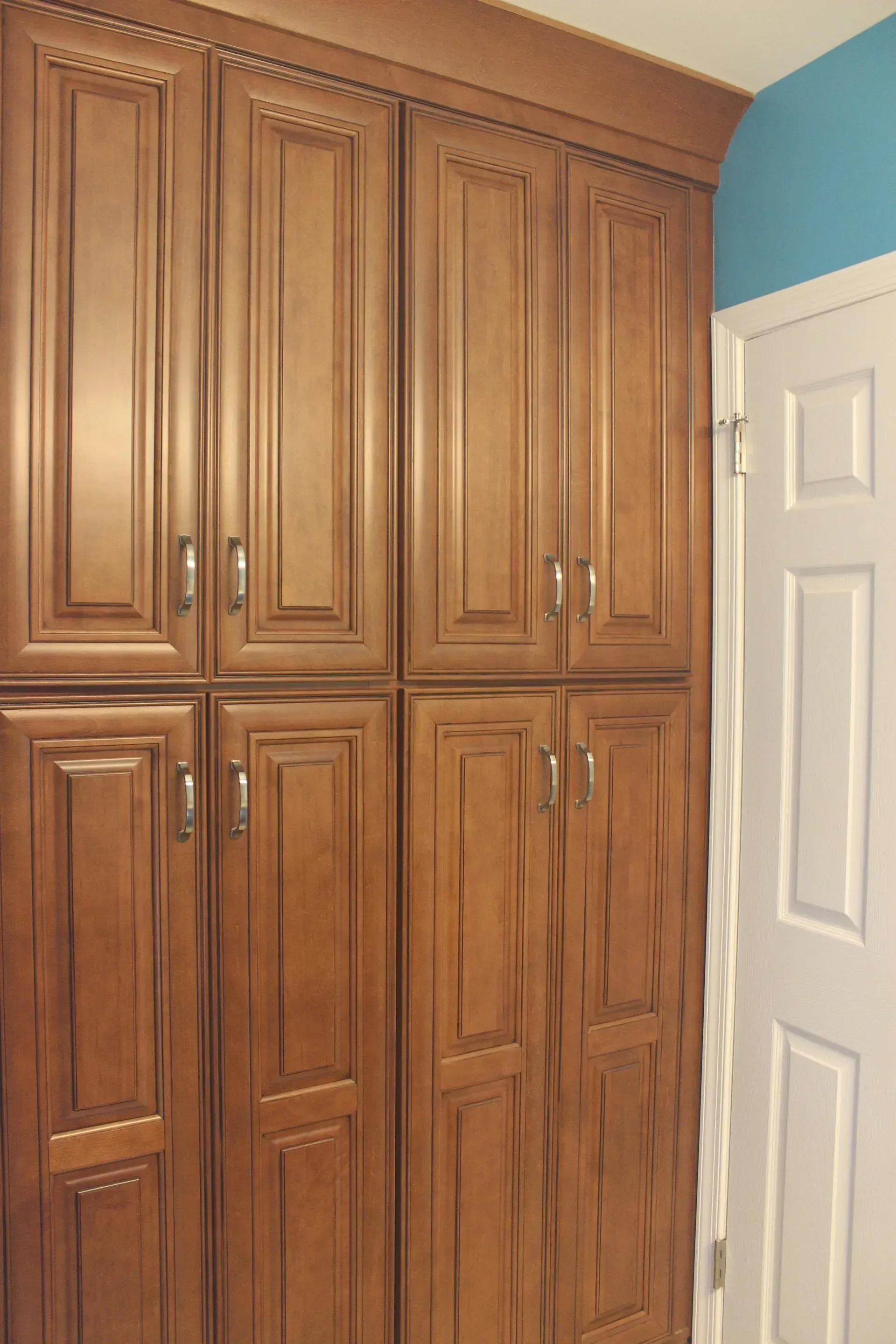Built-in wooden cabinets beside a white door in a room with a blue wall  In Bucks County PA