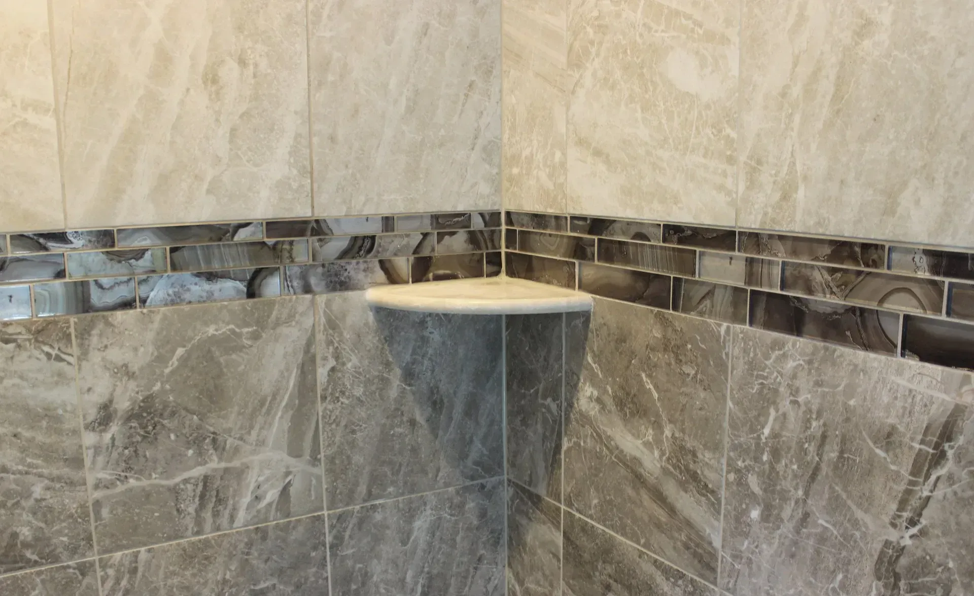Tiled bathroom corner shower with stone-look walls and a small corner shelf or seat  In Bucks County PA