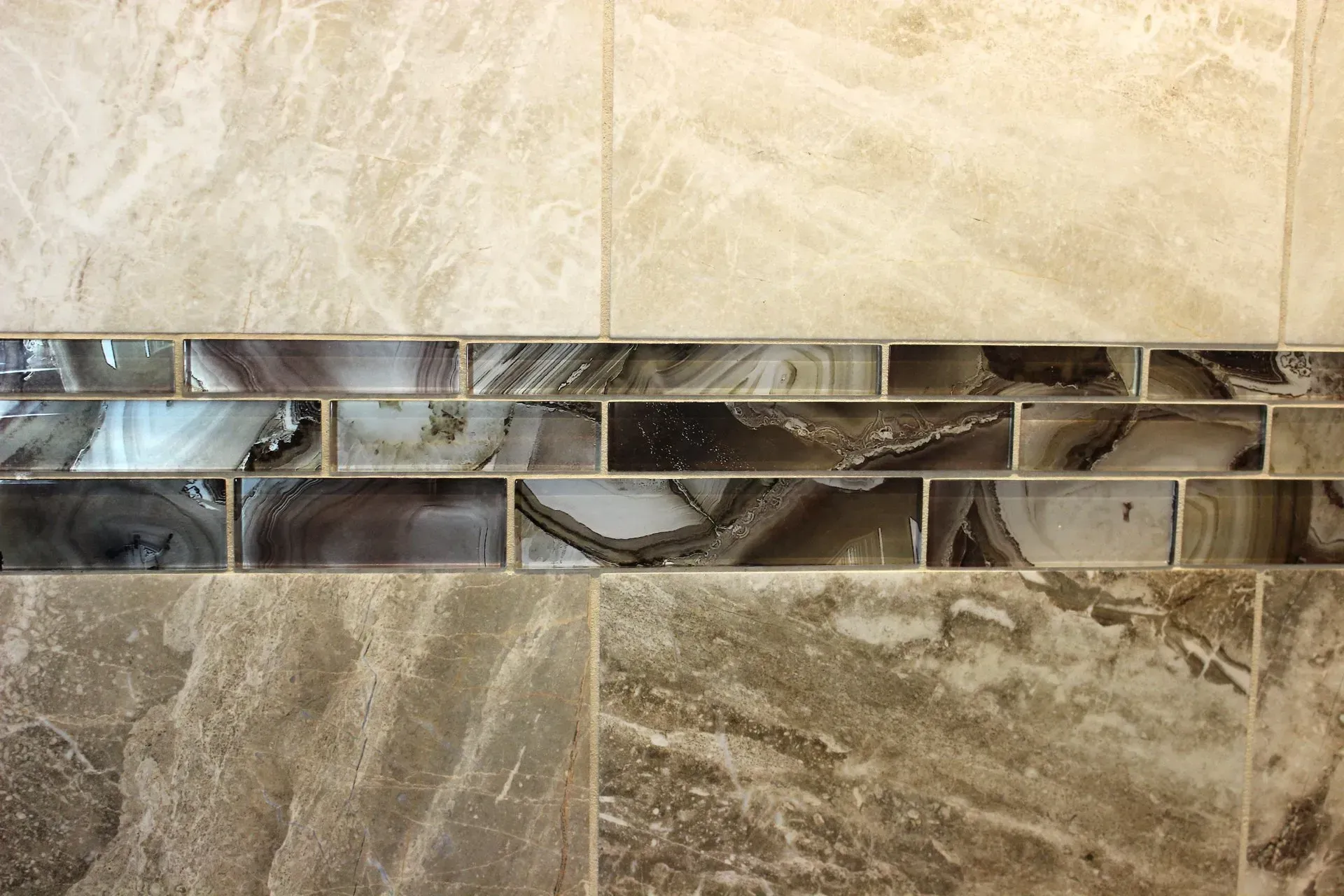 Beige stone tile wall with a horizontal strip of mirrored mosaic tiles  In Bucks County PA