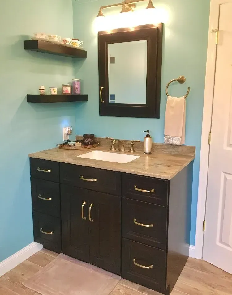 Bathroom vanity with dark cabinets, marble countertop, wall mirror, and blue walls  In Bucks County PA
