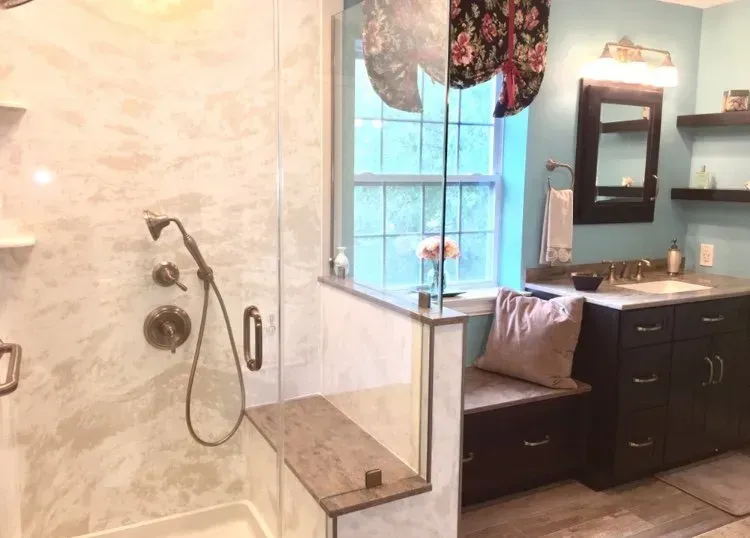 Spa-style bathroom with glass shower, window, and dark wood vanity with sink  In Bucks County PA
