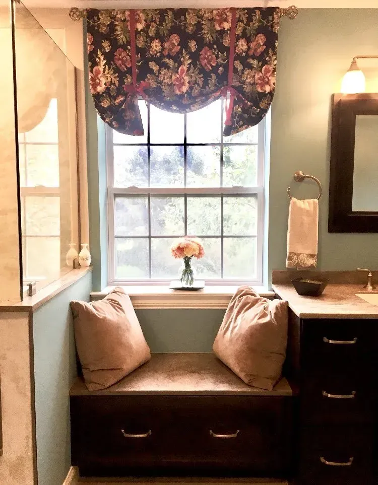 Cozy bathroom window seat with floral valance, tan cushions, and a small vase on the sill  In Bucks County PA