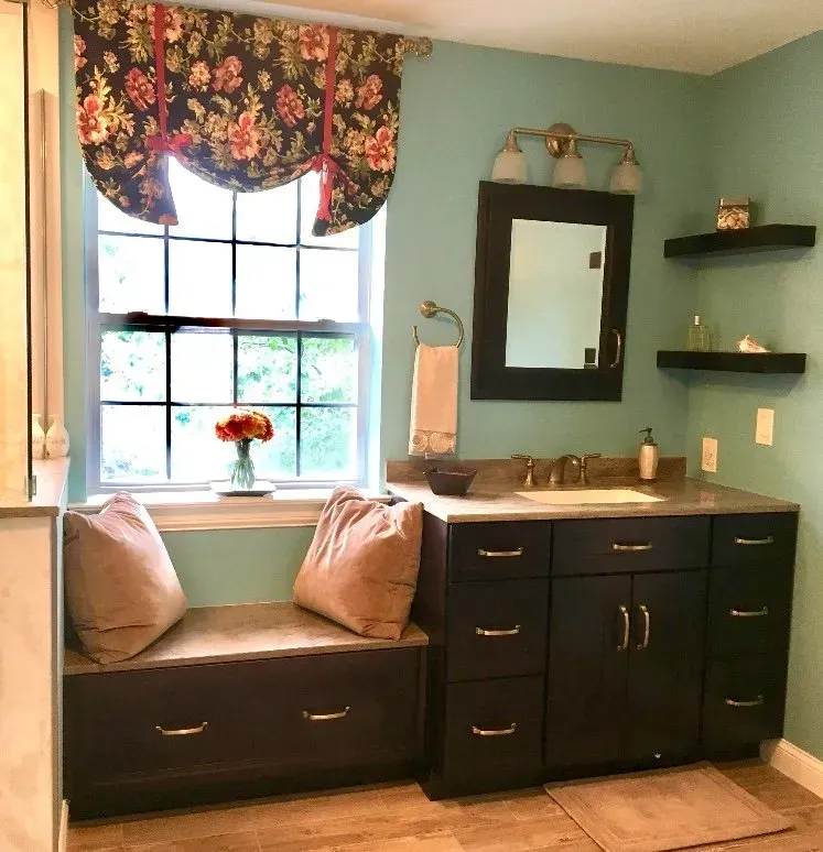 Teal bathroom with window seat, dark vanity, mirror, and wall shelves  In Bucks County PA
