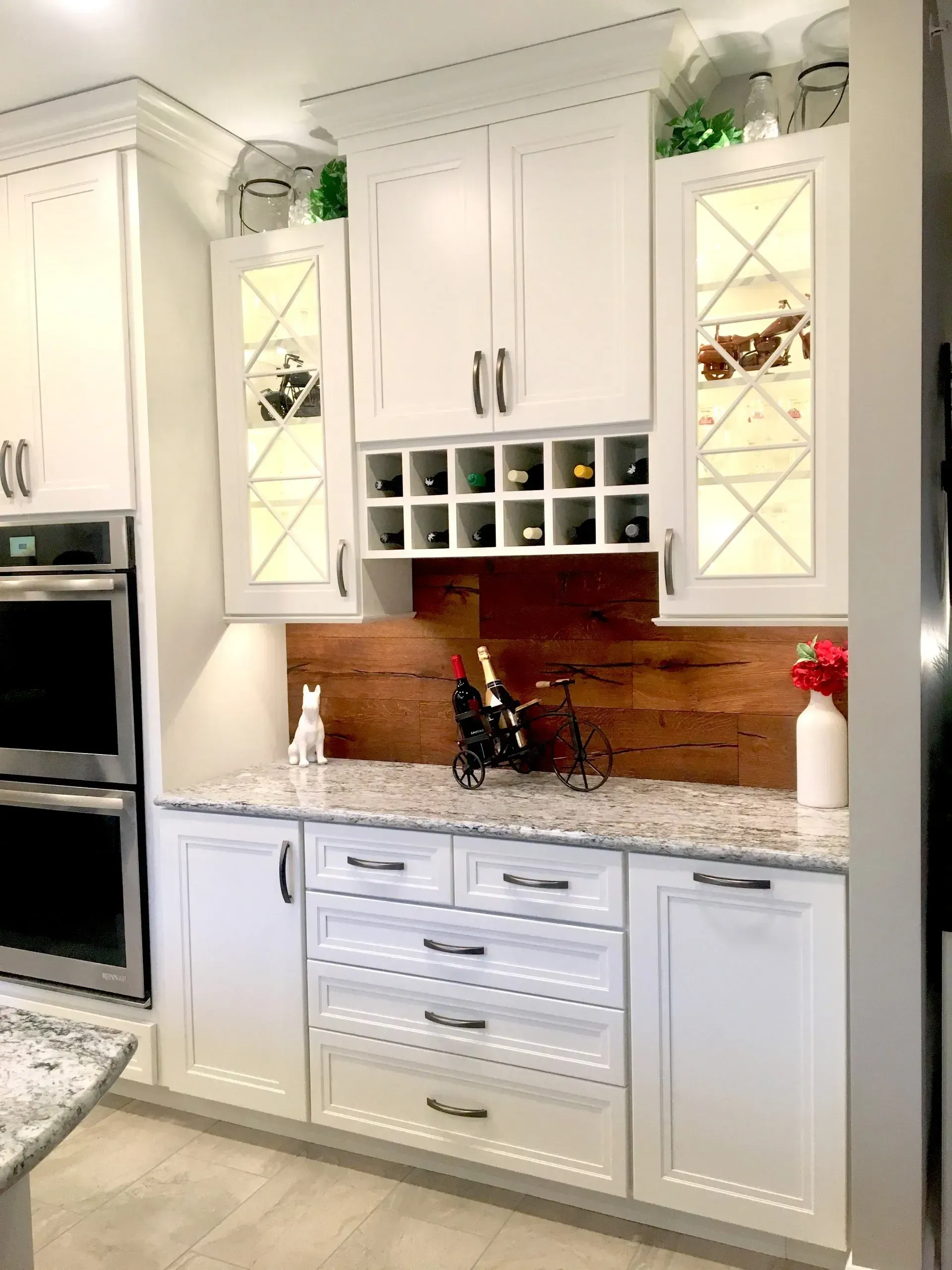 White kitchen cabinets with granite countertop, wine rack, and glass-front display cabinets above the sink In Bucks County PA