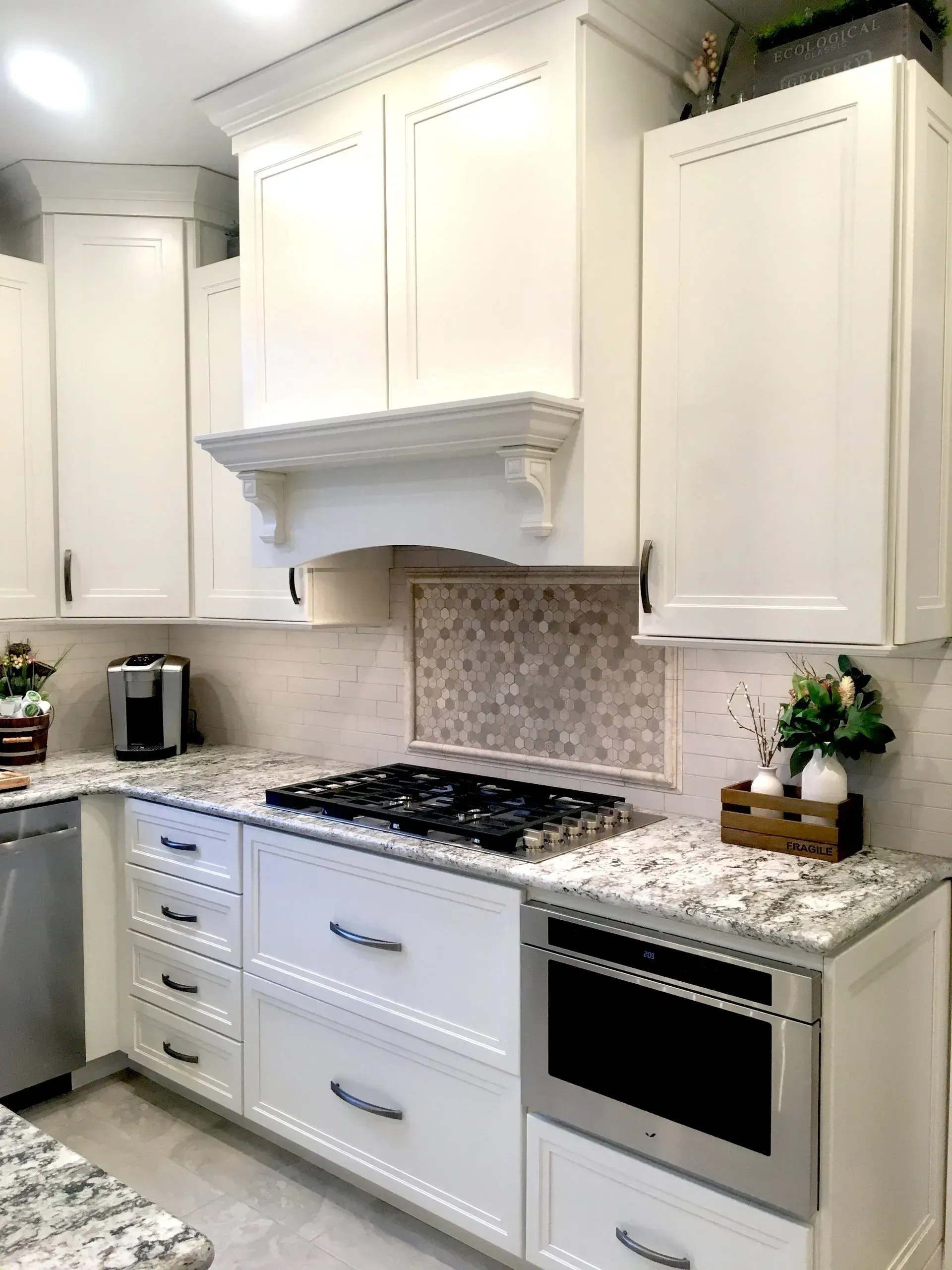 Bright white kitchen with marble counters, gas cooktop, oven, and white cabinets In Bucks County PA